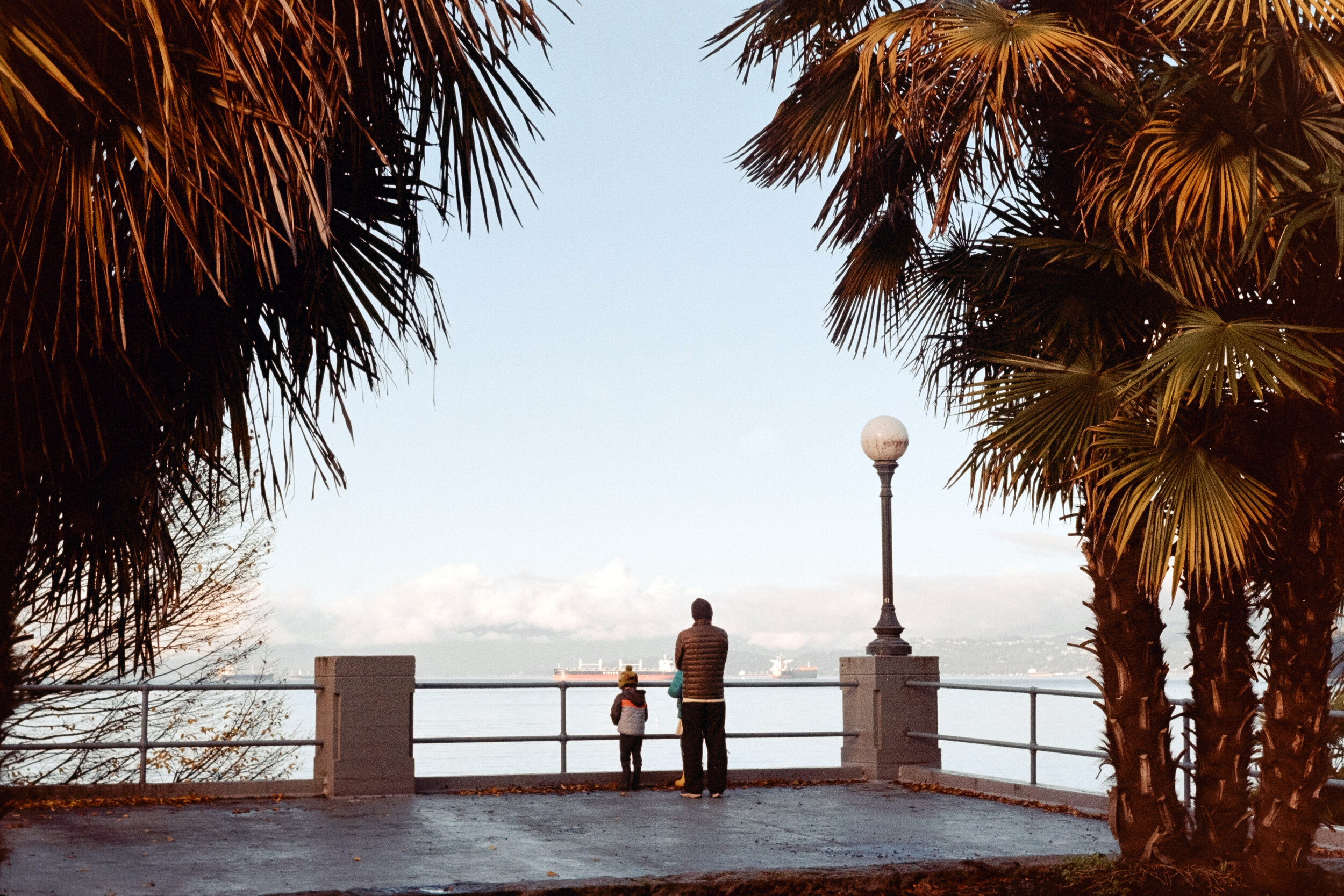 Father and daughter takes in the view at English Bay. Sample image from a Nikon EM and Kodak Gold 200
