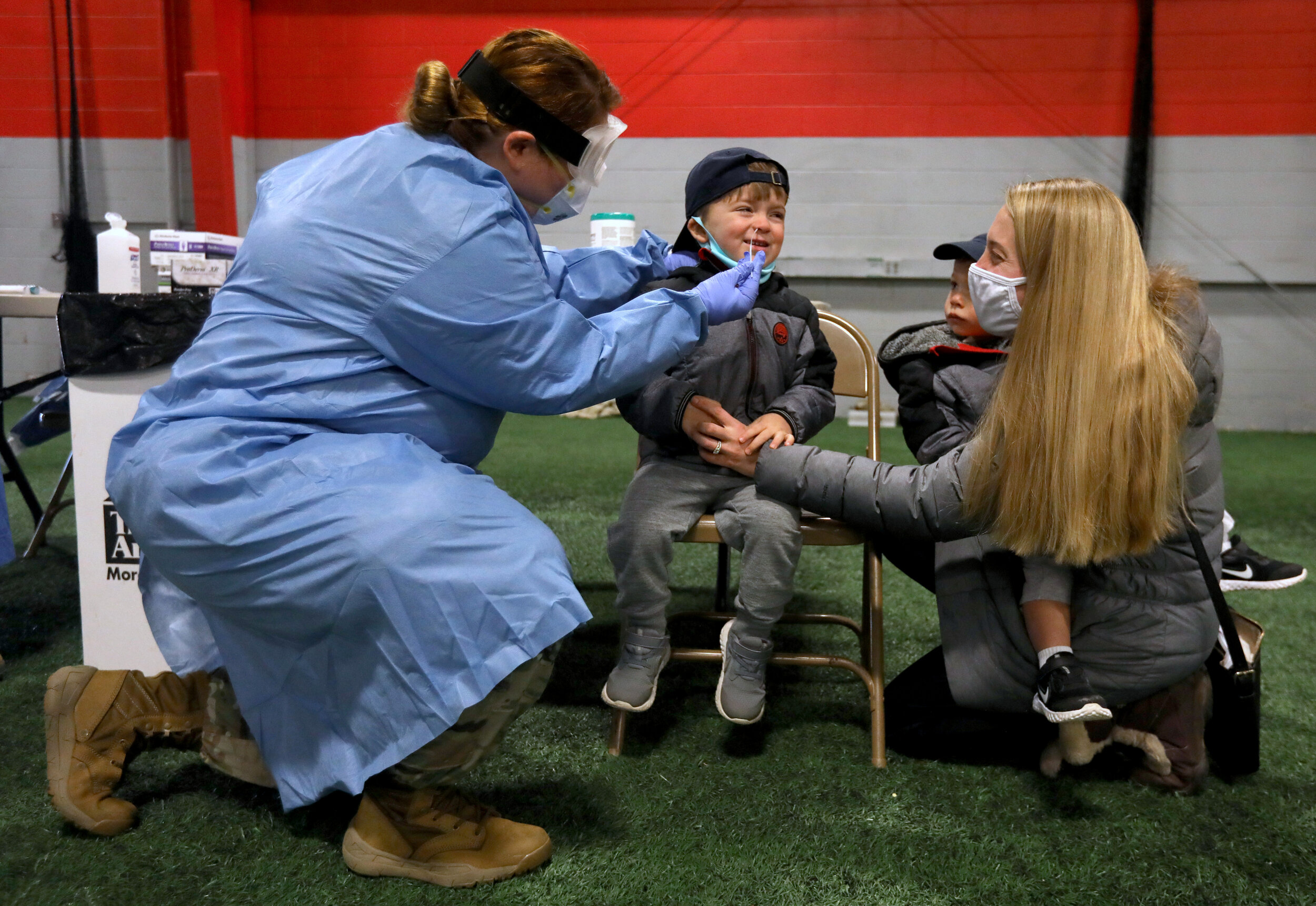  Finn McDonald, 3, is tested for the coronavirus by Army Cpl. Nikki Sherman at the Lucas County Rec Center in Maumee. Watching is his brother, Shay, 1, who was too young to be tested, and their mother Casey McDonald.  ©Toledo Blade | December 2020 