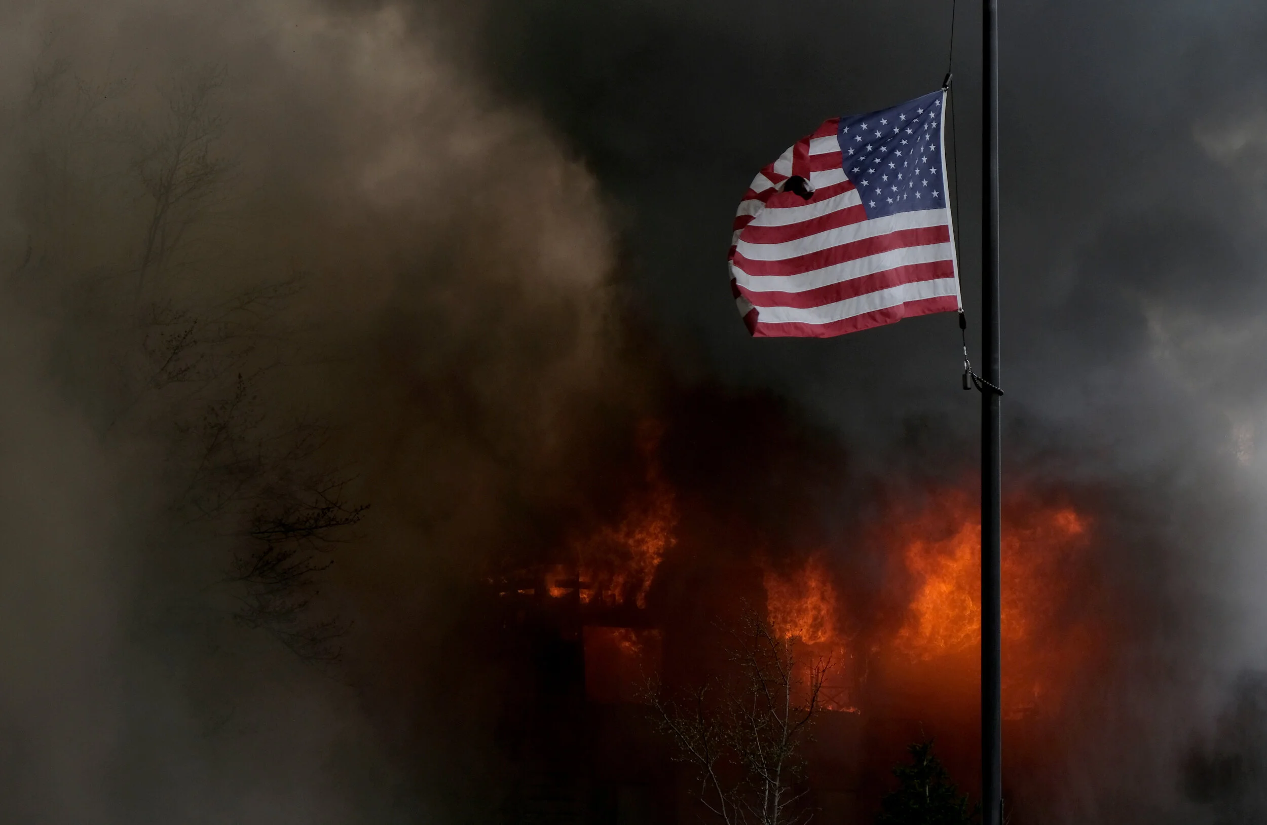 A flag for the Swan Creek Retirement Village flies in front of an apartment fire at 5900 block Cresthaven Lane in Toledo. © Toledo Blade | March 2021