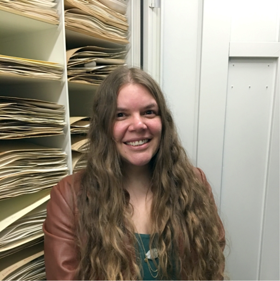 AJ standing in front a cabinet of dried, pressed plant specimens at the National Museum of Natural History of the United States.