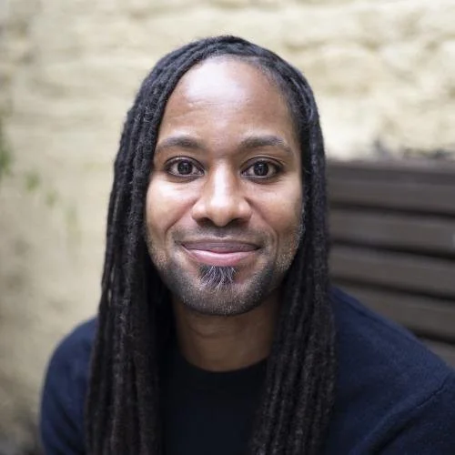 Jason Arday, a smiling black man with long dreads