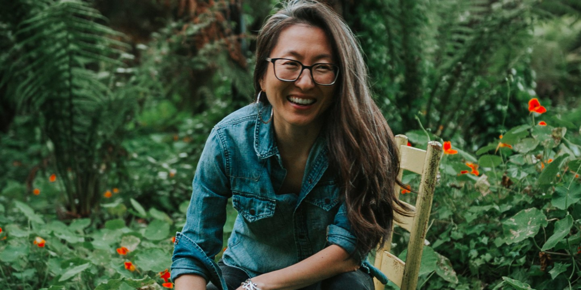 A smiling Korean woman with glasses and long hair