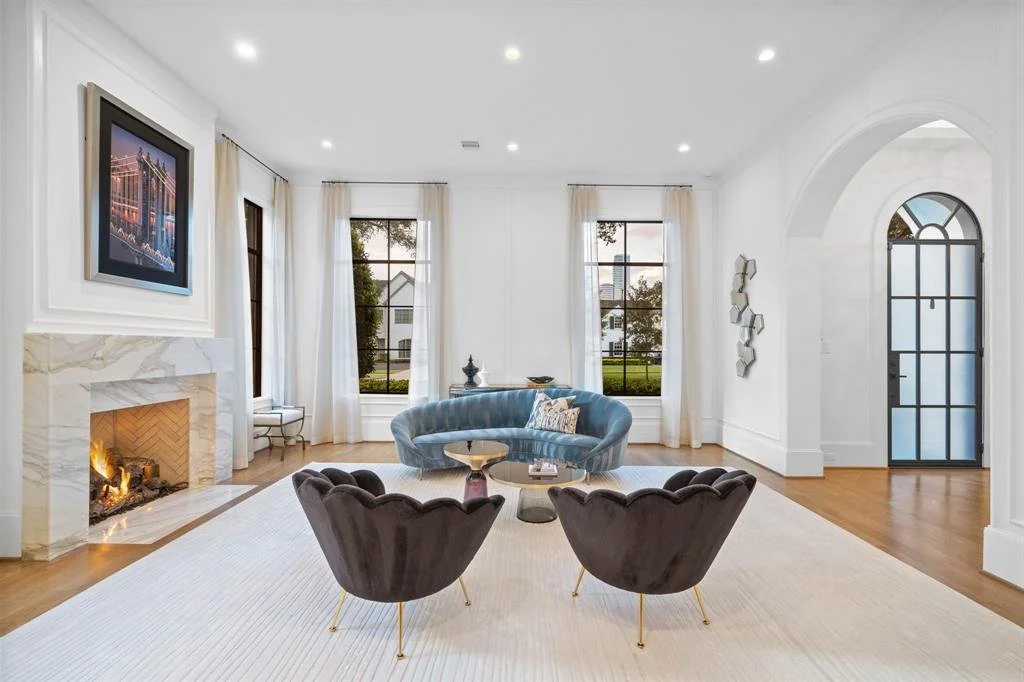 Formal living room with modern furniture, white walls, and a marble fireplace.