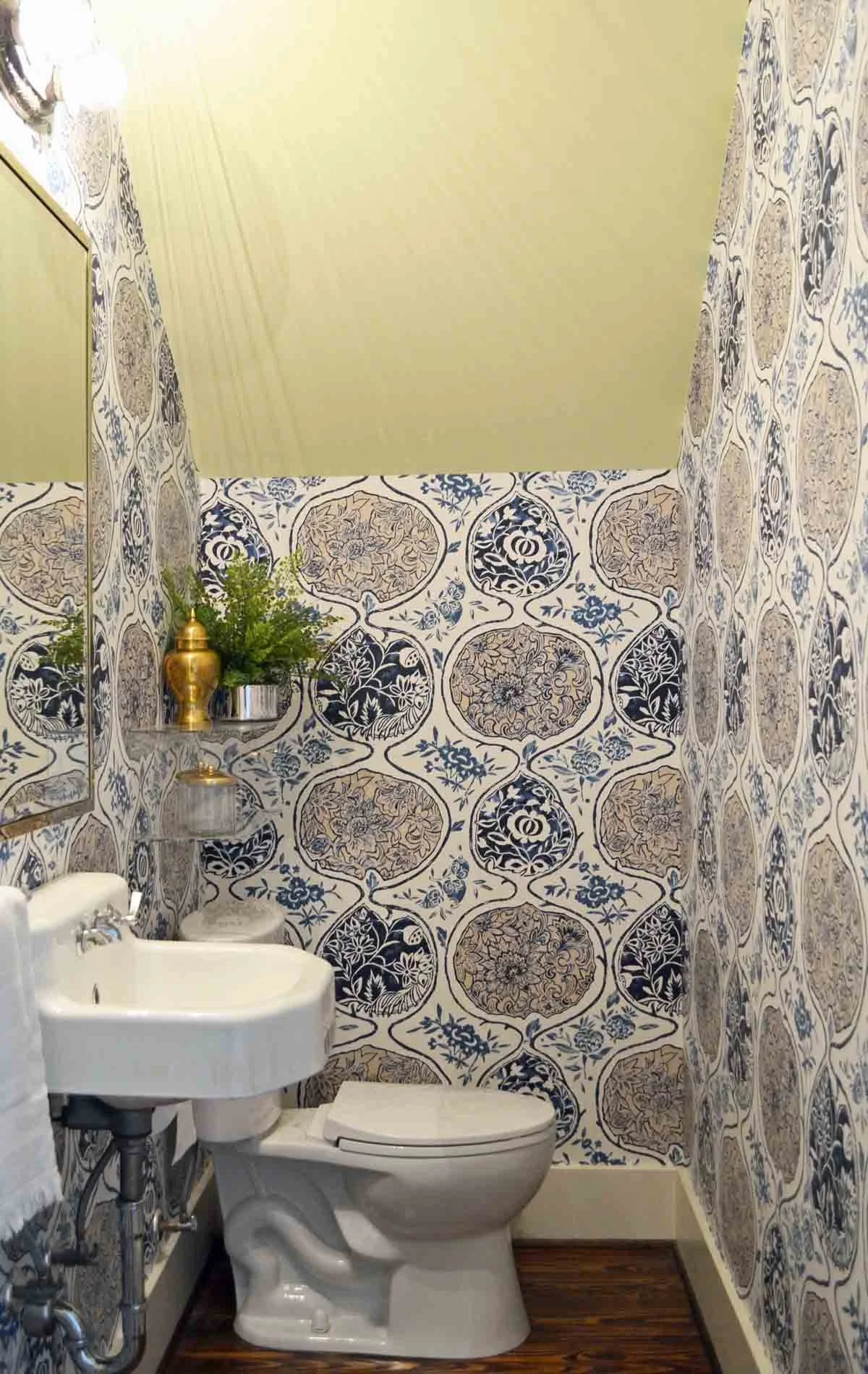 Bold wallpaper wraps a tiny powder bathroom with a reclaimed wall hung sink