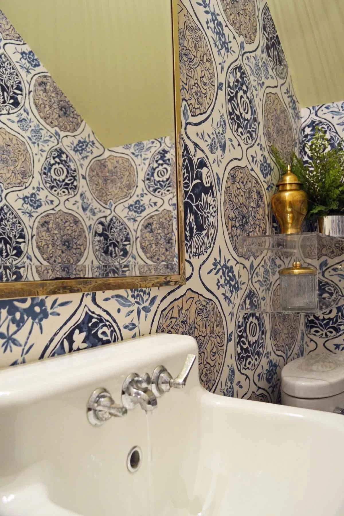 Antique reclaimed wall-hung sink with bold wallpaper in a historic home renovation