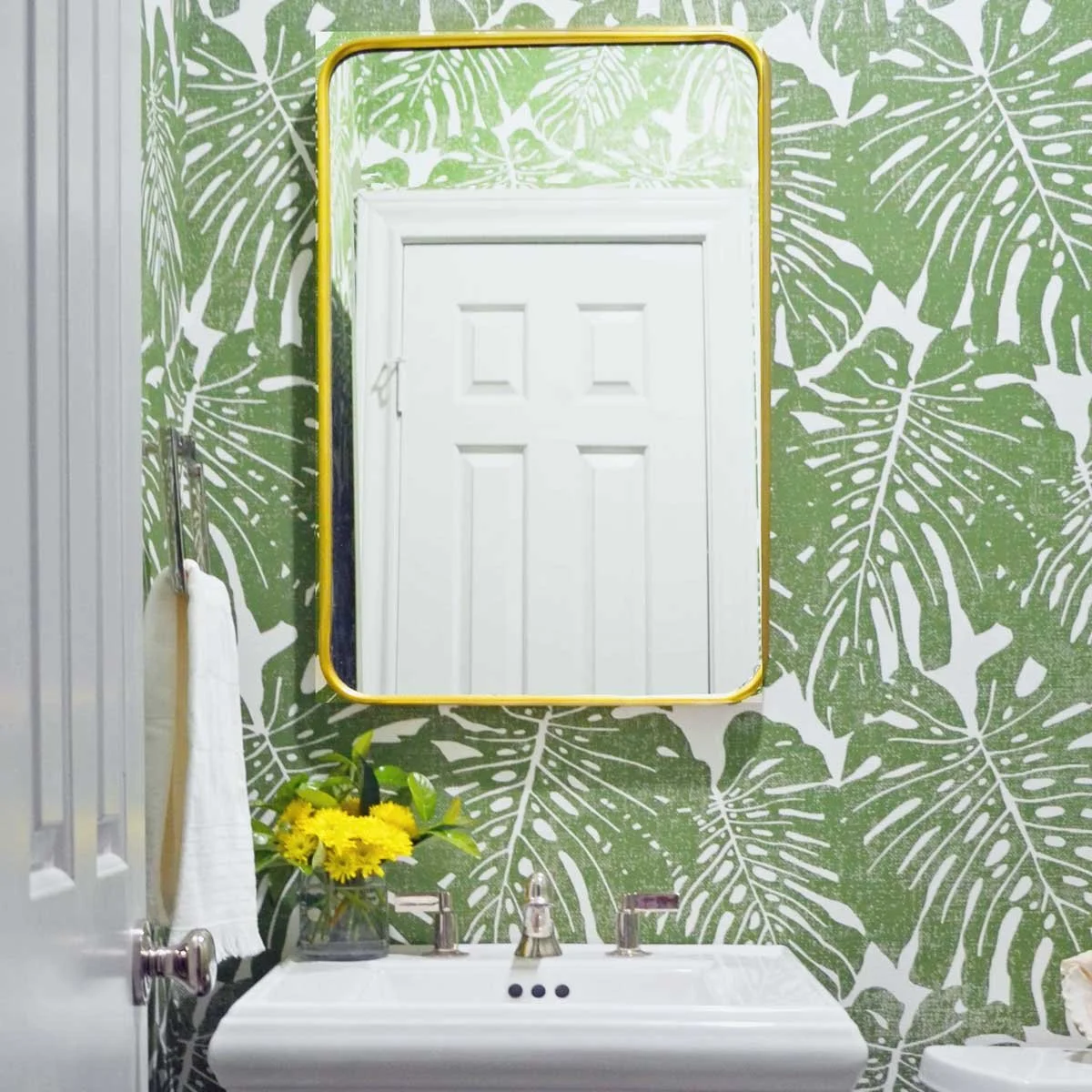 Powder bathroom design in Centennial CO showing warm brass mirror with polished nickel plumbing against a bold wallpaper by Jamie House Design