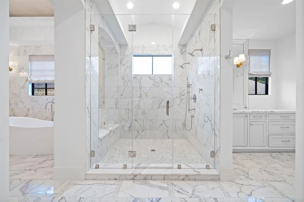 Expansive luxurious marble double shower in this Highlands Ranch primary bathroom