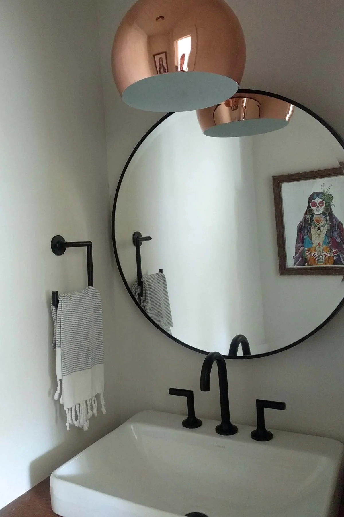 Mixed metal light fixture in bathroom showing copper and black plumbing fixtures
