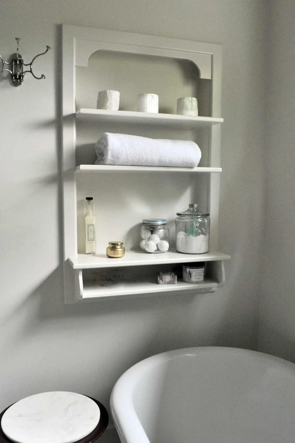 Built-in shelf near bathtub in primary bathroom renovation is a reclaimed phone shelf