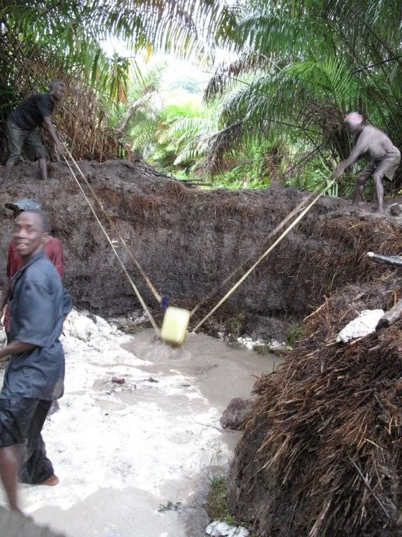 In order to remove the diamond bearing material, the flooded out pits need to constantly be drained. This is done, in this case, the old fashioned way, with a bucket - but modified for efficiency.
