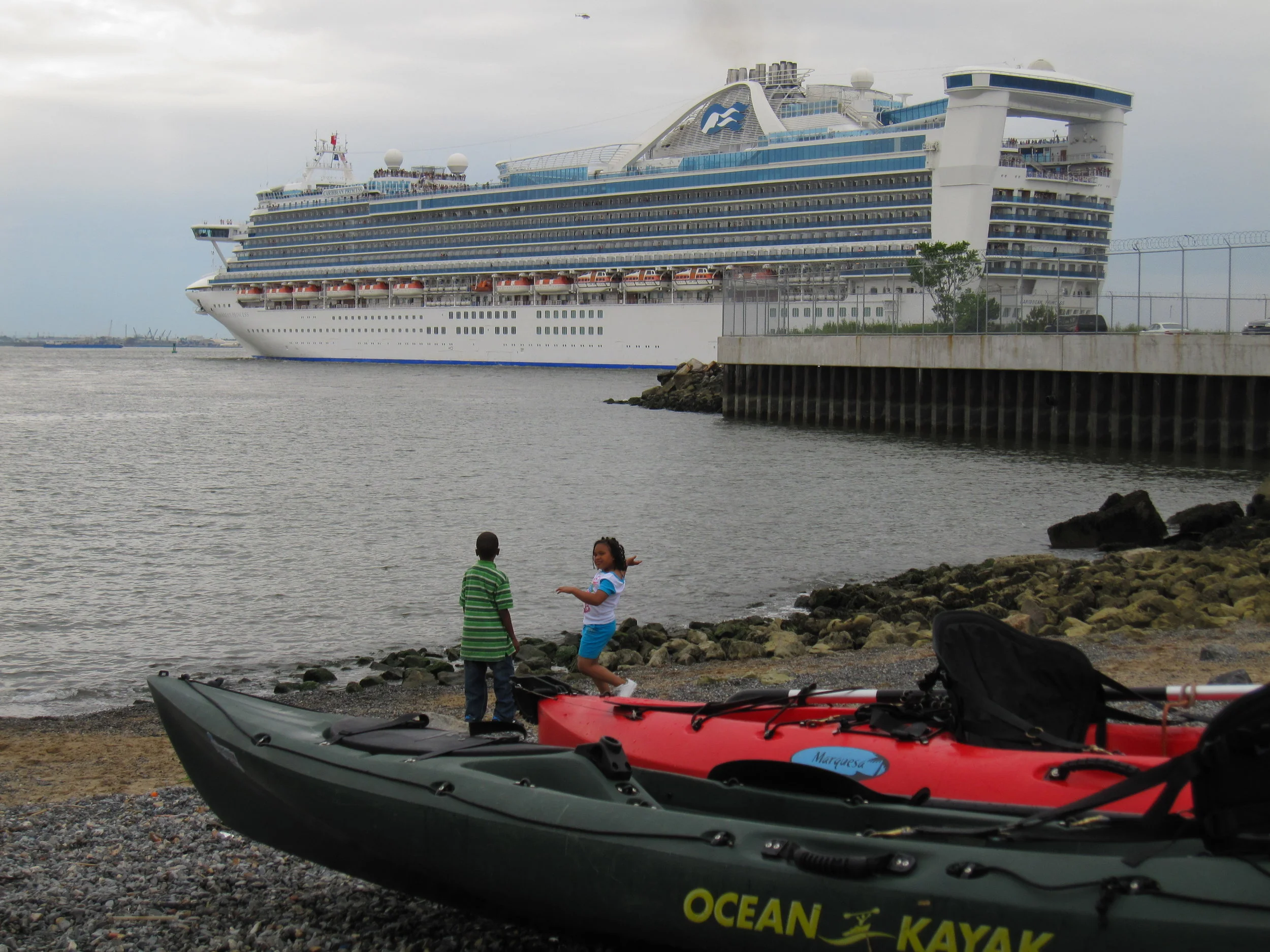 A cruise ship leaves the Brooklyn Cruise Terminal in Red Hook, close to the Valentino Park beach where kayaks come and go, an example of the huge difference in scale of boats in close proximity on NYC waterways.