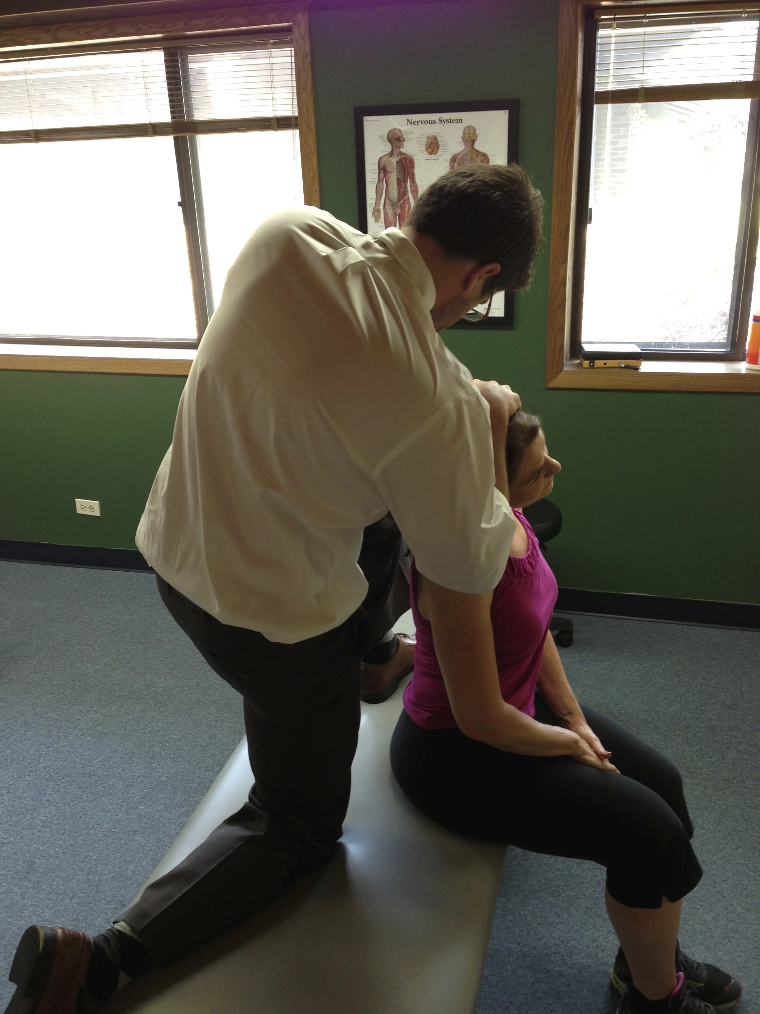 Dr. Chris Examines someone experiencing cervicogenic headaches at our Victory Rehab office in Naperville.
