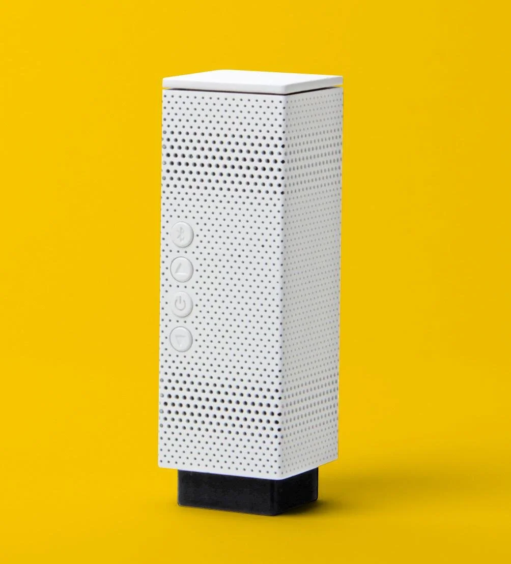 A white rectangular electronic device with perforated sides and four control buttons, placed against a yellow background.