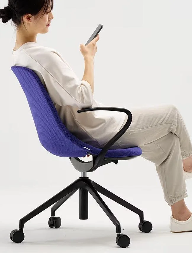A woman sitting in a blue office chair, looking at her smartphone against a plain white background.
