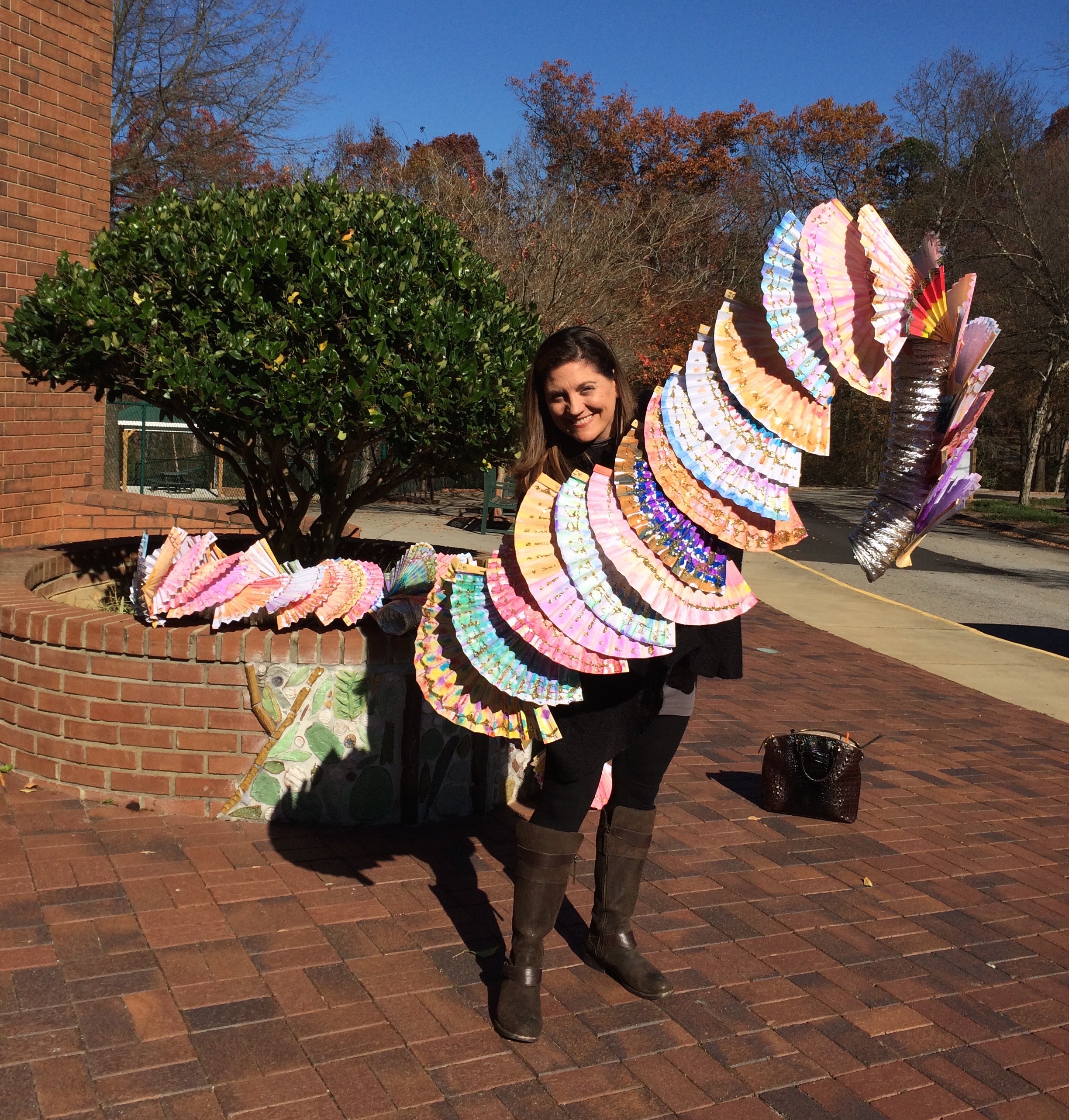 Allison Spinks holding a section of a dragon that consists of hand painted fans over flexible dryer pipe.