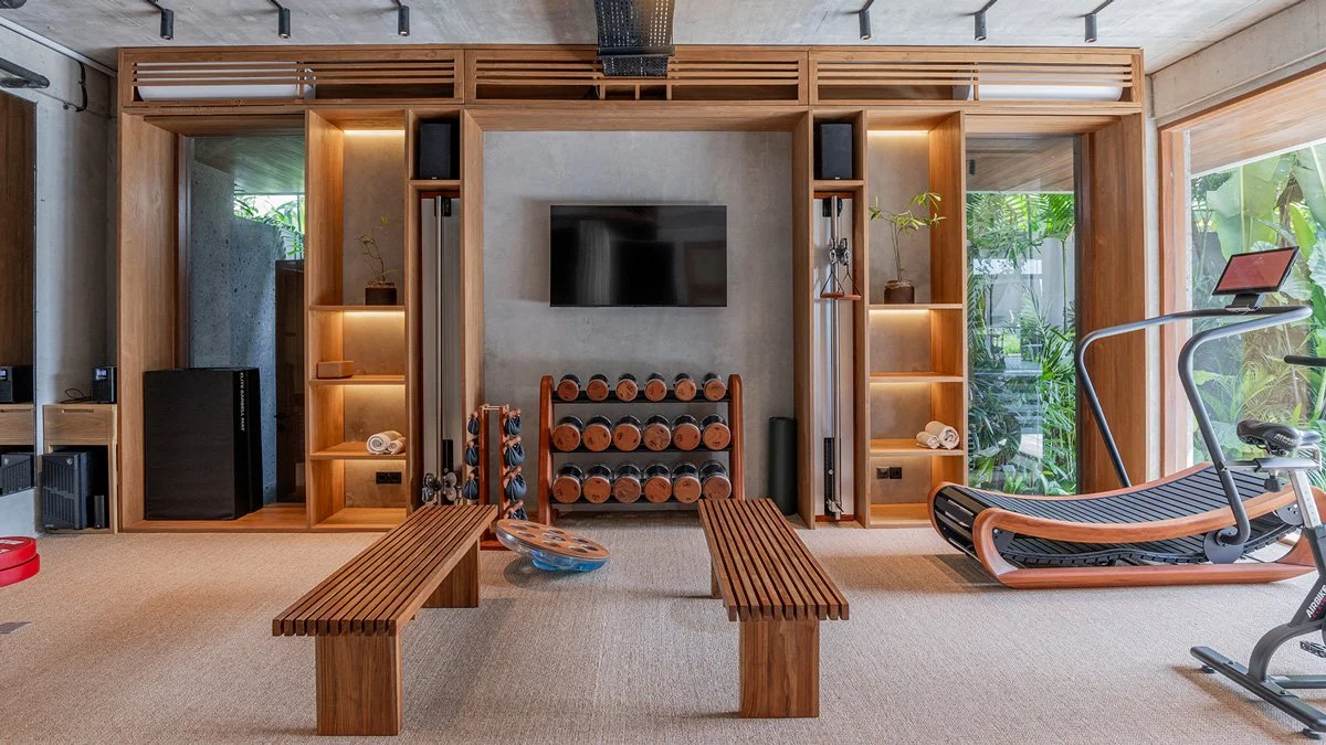 Luxury home gym with custom walnut millwork, NOHrD wooden dumbbells and Sprintbok treadmill, and integrated Eleiko strength equipment