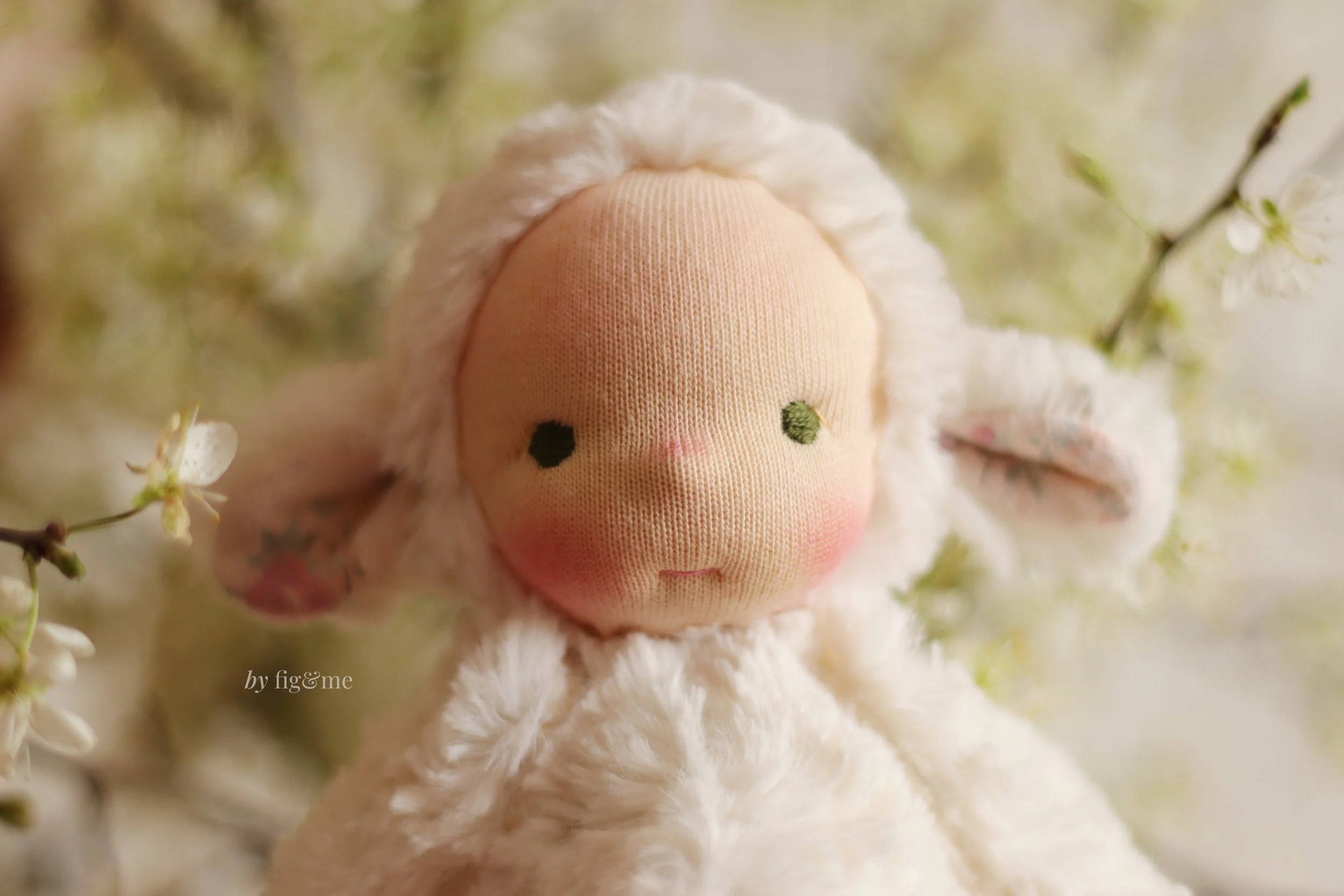 closeup of white art doll lamb with green eyes and fair skin by fig and me