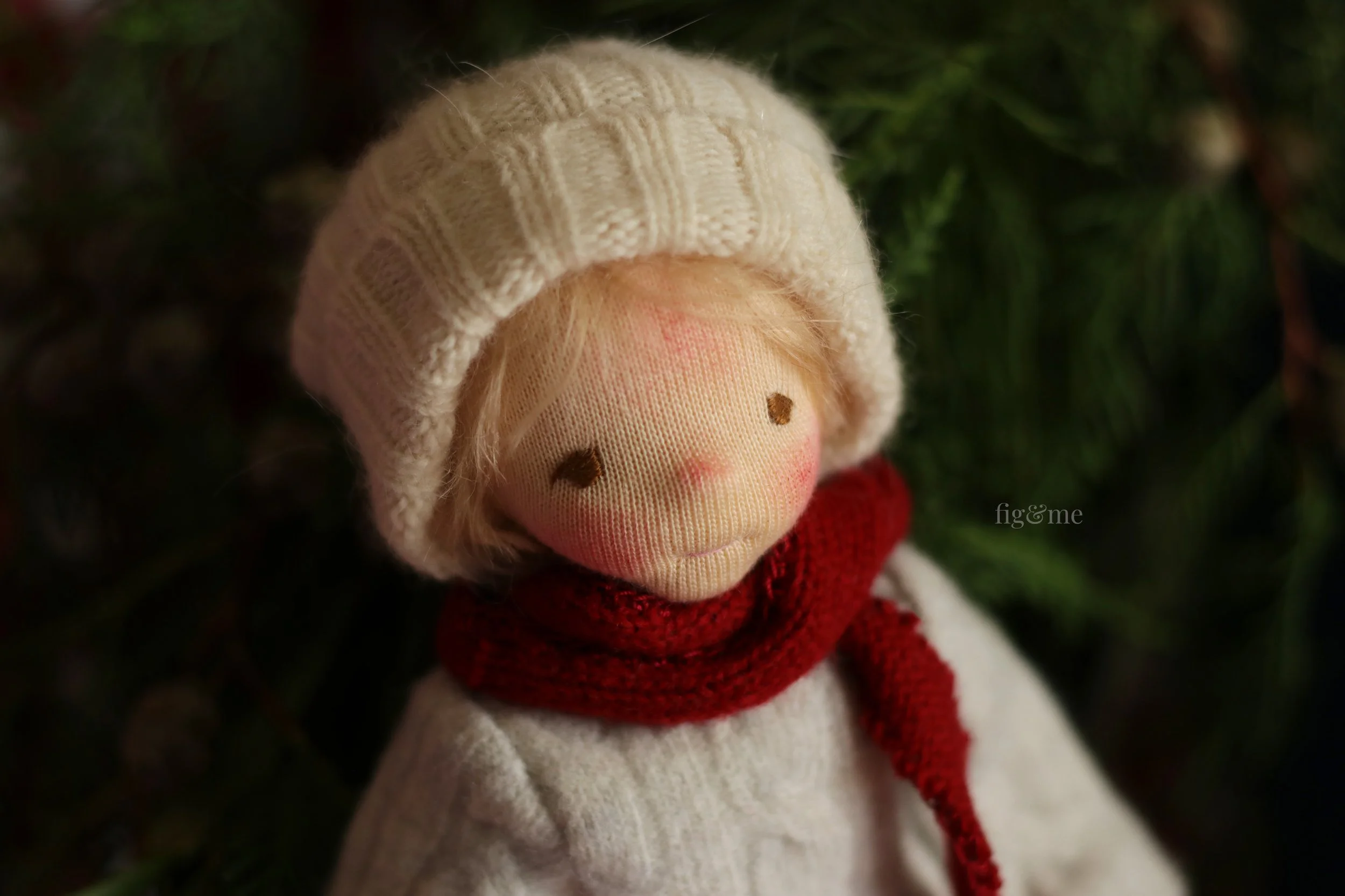 blonde fiber art doll with red scarf and white beanie