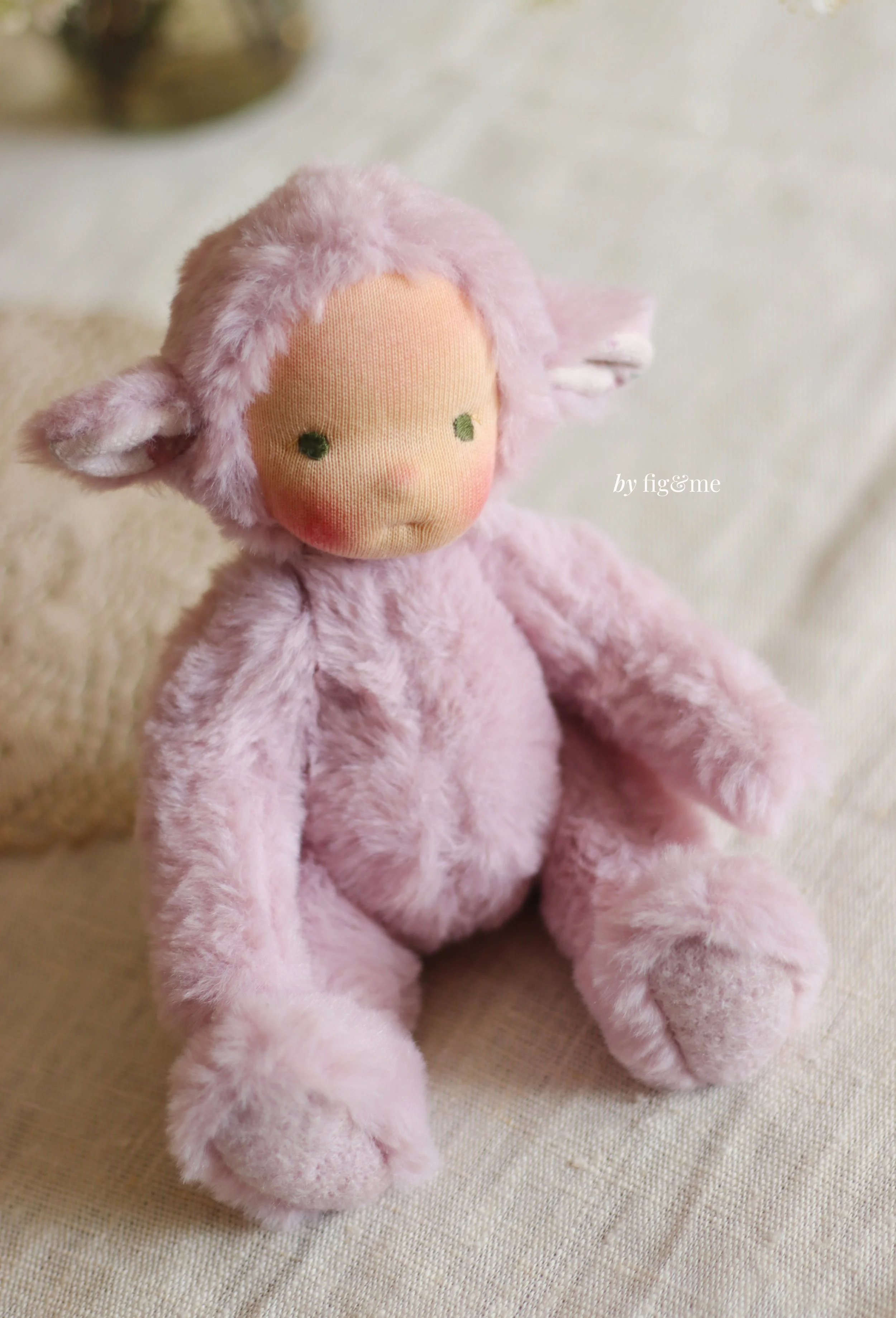 soft pink fur art doll lamb sitting on white linen tablecloth