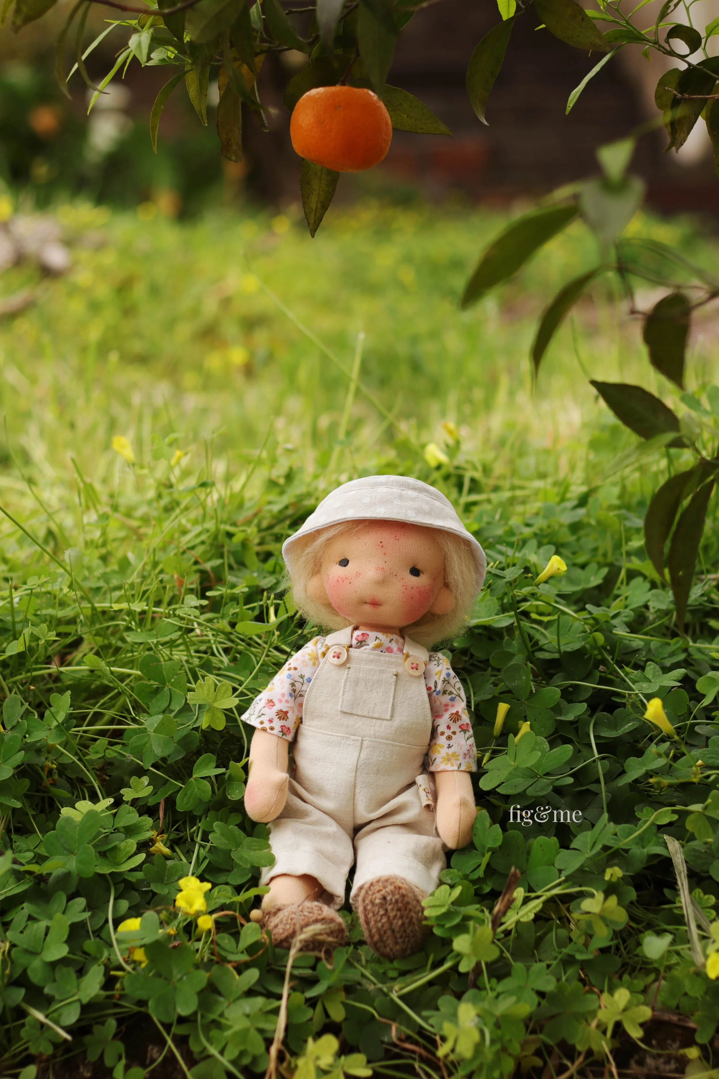 Waldorf inspired doll, sitting on a Portuguese garden, under a mandarin tree