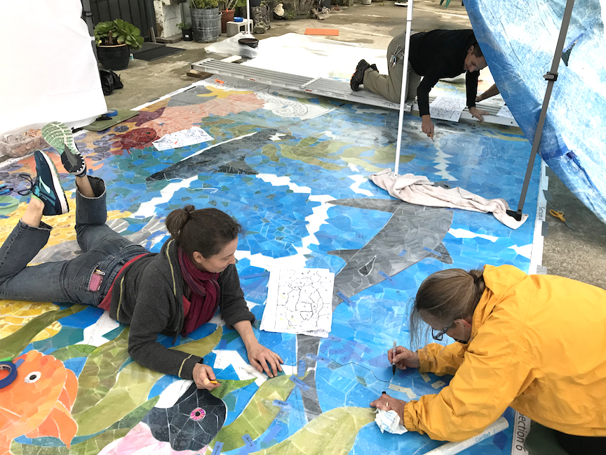 Getting it done under tarps before the pour down. FYI - never lay on a glass mural.