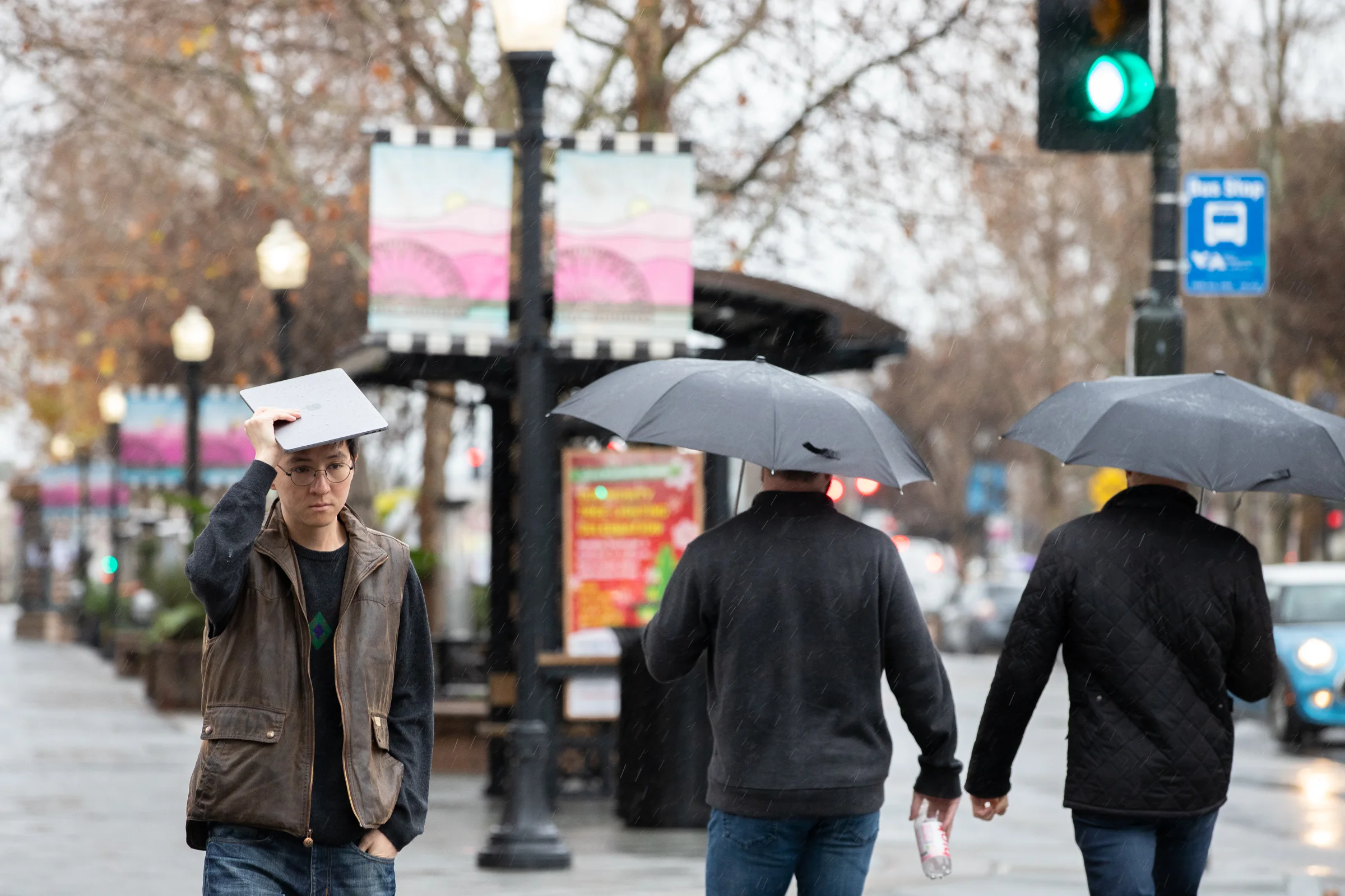 A man walking downtown in the rain on Castro Street in Mountain View, California, uses a MacBook Pro to keep dry on Jan. 15, 2019.