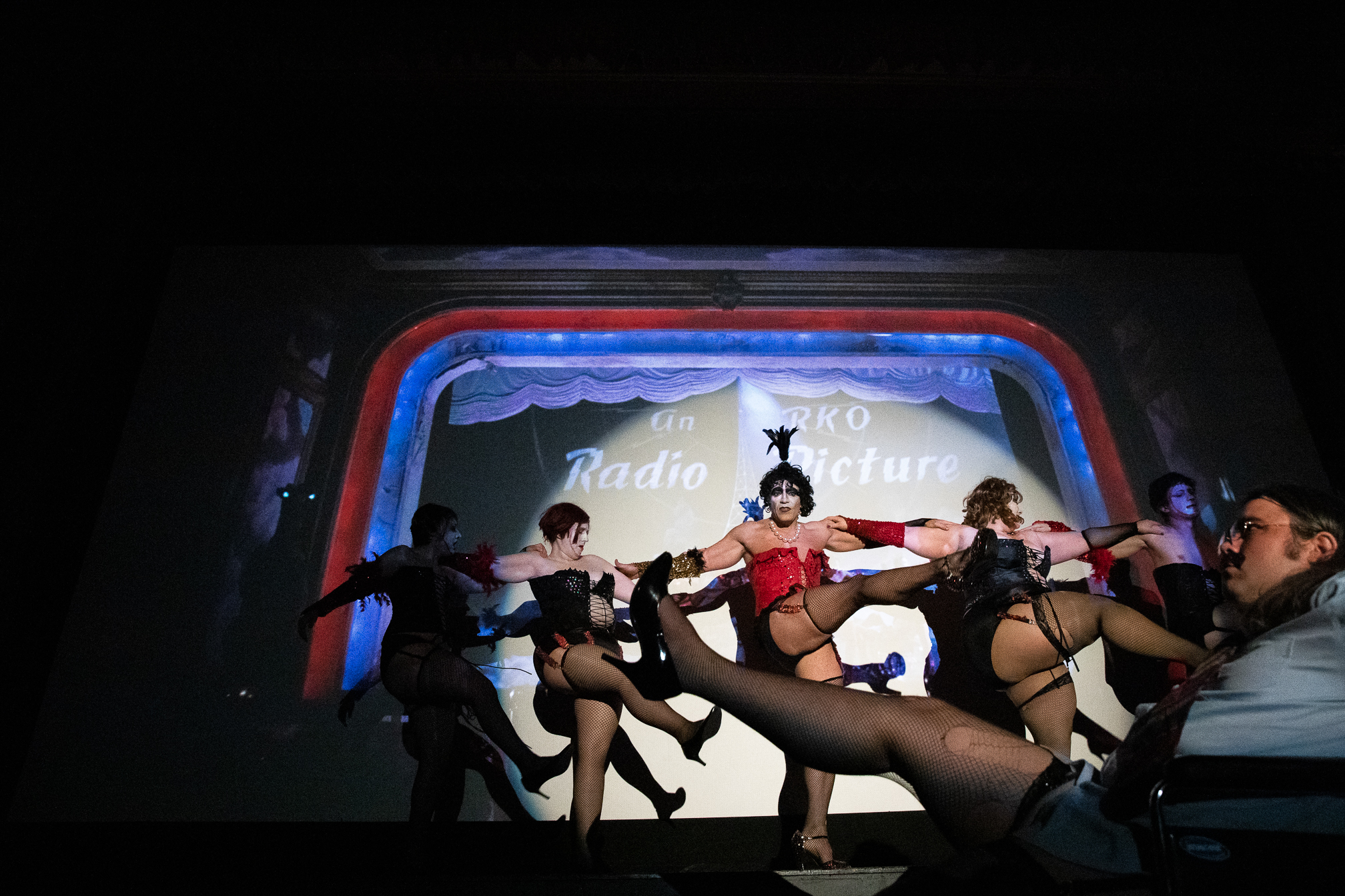 The Bawdy Caste actors perform the cabaret scene in front of the projected film during a midnight showing of “The Rocky Horror Picture Show” at the Guild Theatre on April 6.