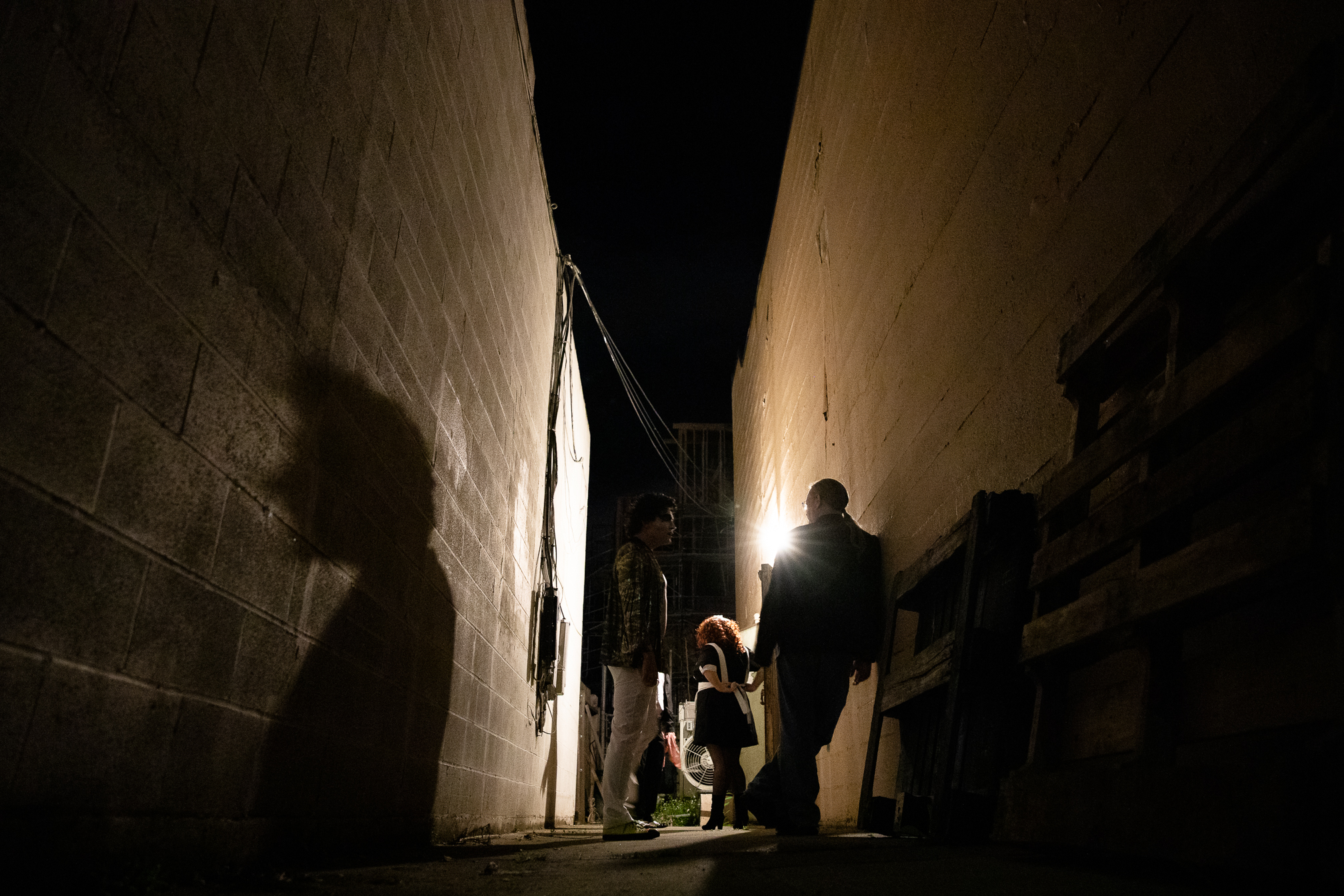 Bawdy Caste performers and crew members relax in an alley lining the side of the Guild Theatre before the start of the midnight showing.