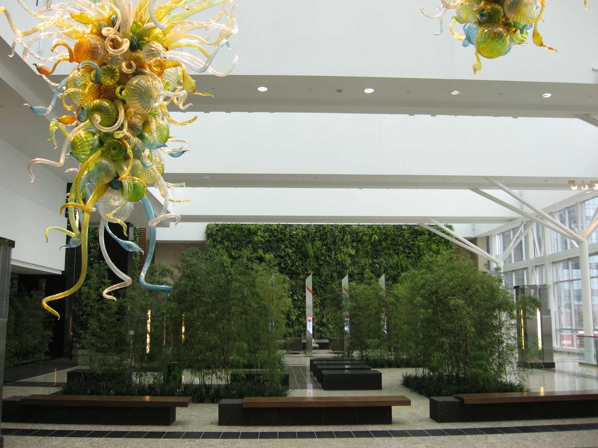 The Winter Garden at Jamieson Place offers a tranquil place to sit, relax and reflect. The Green Wall in the background is 22 ft hight and 100 ft wide and has over 20,000 plants. It was designed by McRae Anderson of McCaren Designs who chose plant types, leaf shapes, sizes and textures to mirror the topographical changes in the land around Calgary as you move from prairie grasslands to foothills to mountains. In the foreground is one of three Dale Chihuly glass sculptures that hang over the infinity ponds. 