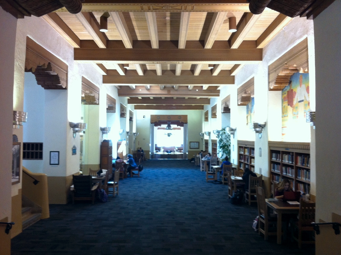 The hallway of the original wing with its rich carpet, wood book cases, murals and decorative ceiling.