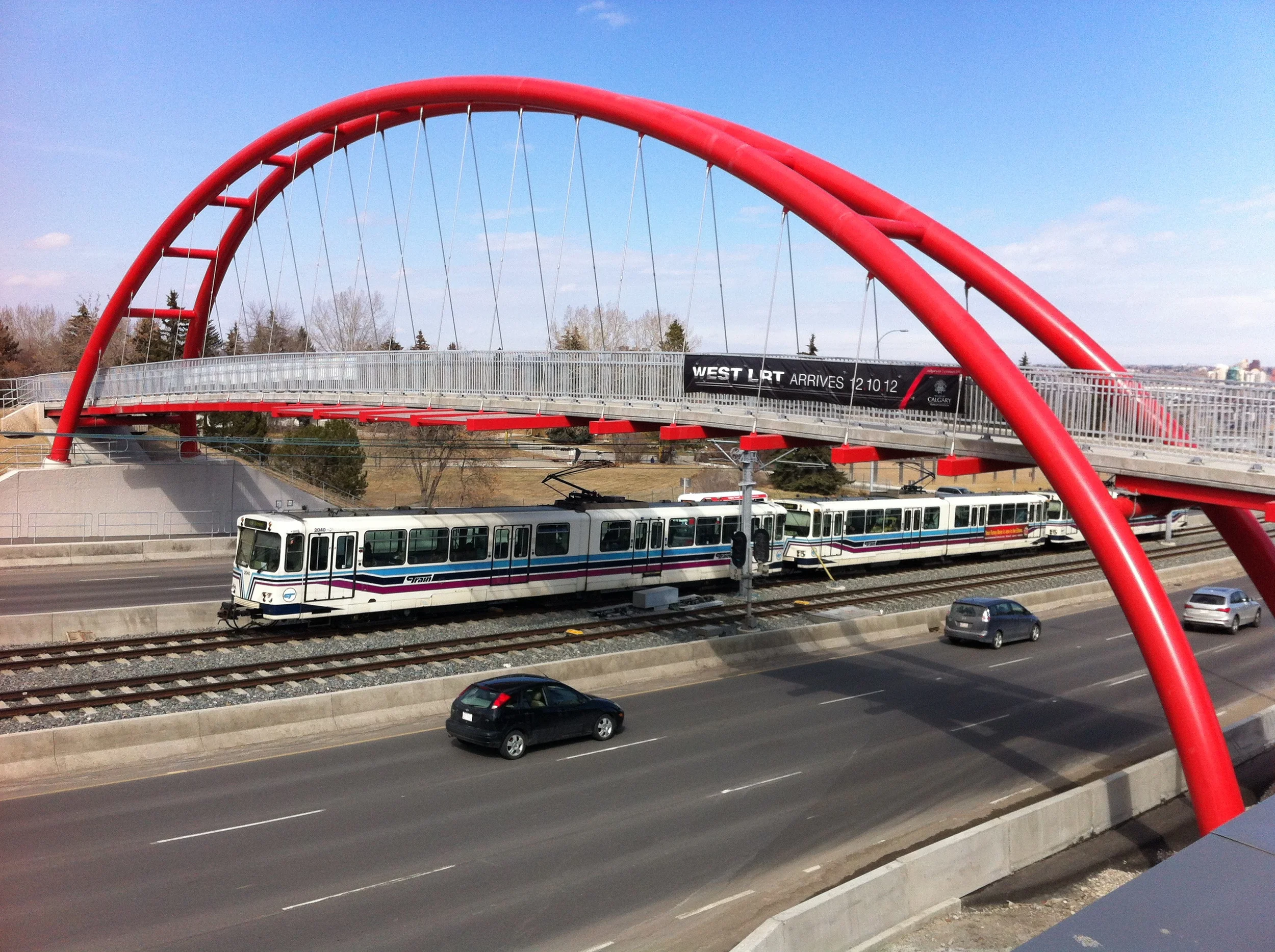 The bridge spans the river of buses, trains and automobiles entering and exiting the Downtown along Bow Trail. 