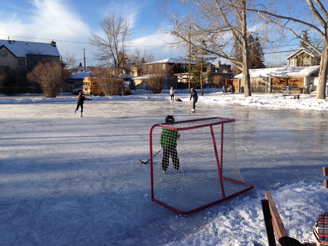 This DIY outdoor rink is being used by two figure skaters, as well as a mom and her son playing hockey and several people watching. Too bad City of Calgary limits the number of people who get access to fire hydrants for flooding the rink in any one community. Why can't there be as many ice rinks as there is demand? 