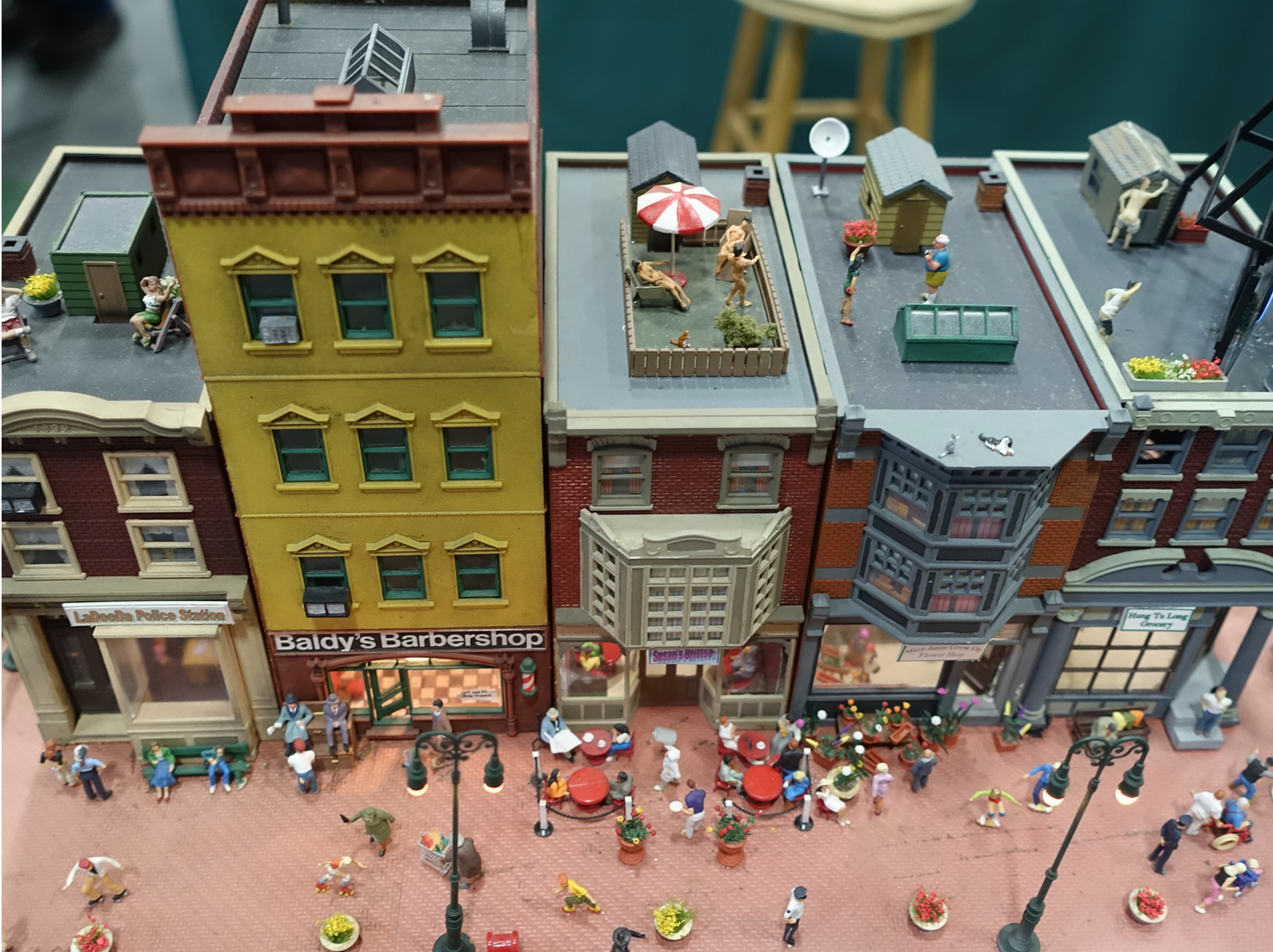 What at first looks like an everyday busy street scene has nude sunbathers on the rooftop, as well as two guys mooning the neighbours. 