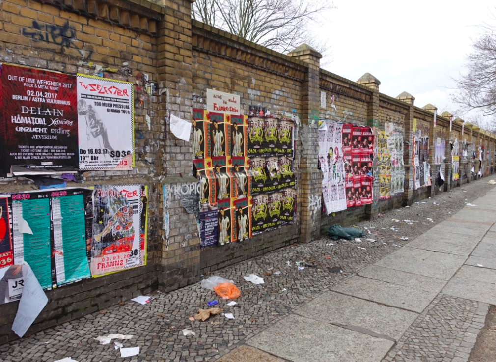 Every wall is plastered with either graffiti or posters; this wall was around a park.