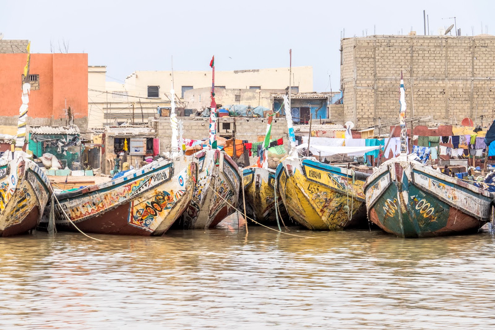 A group of colorful fishing boats in the harbor at St. Louis, Senegal. St. Louis is a major port for Senegal and a large portion of the people earn their living from the sea. Much of the fishing is done at night and the boats return in the morning to sell their catch.