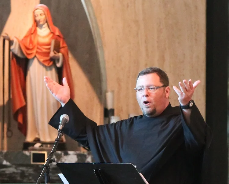 Fr. Rich Young, O.S.A. leads music at St. Rita of Cascia High School, Chicago, near a statue of St. Monica