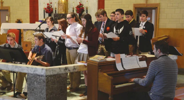 Fr. Brian (at the piano) encourages student participation in music ministry for the school Masses and prayer services.