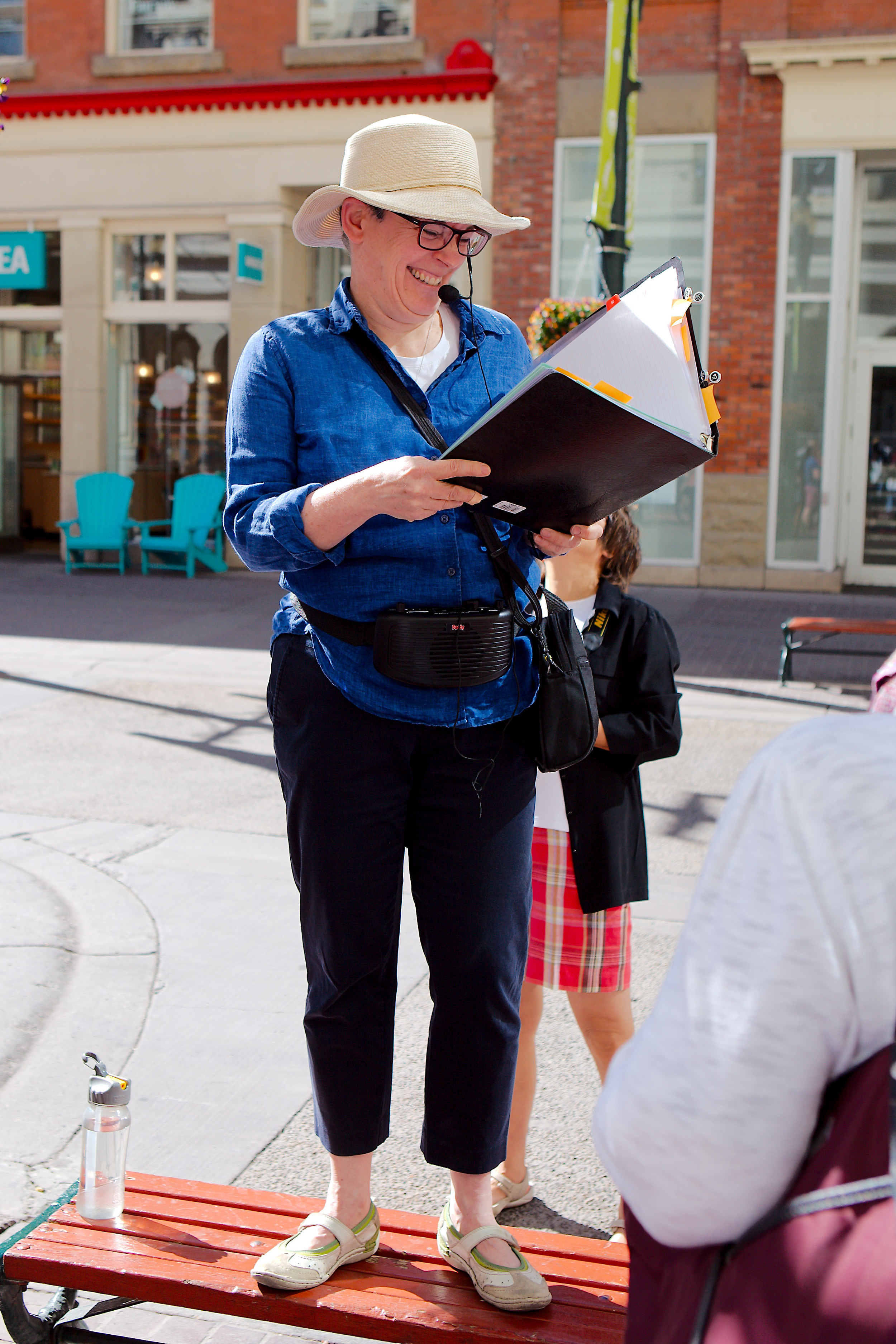 Life is good when you get to wear a headset, stand on a bench and tell Calgary stories in the sun. (Photo: Reg Tiangha)