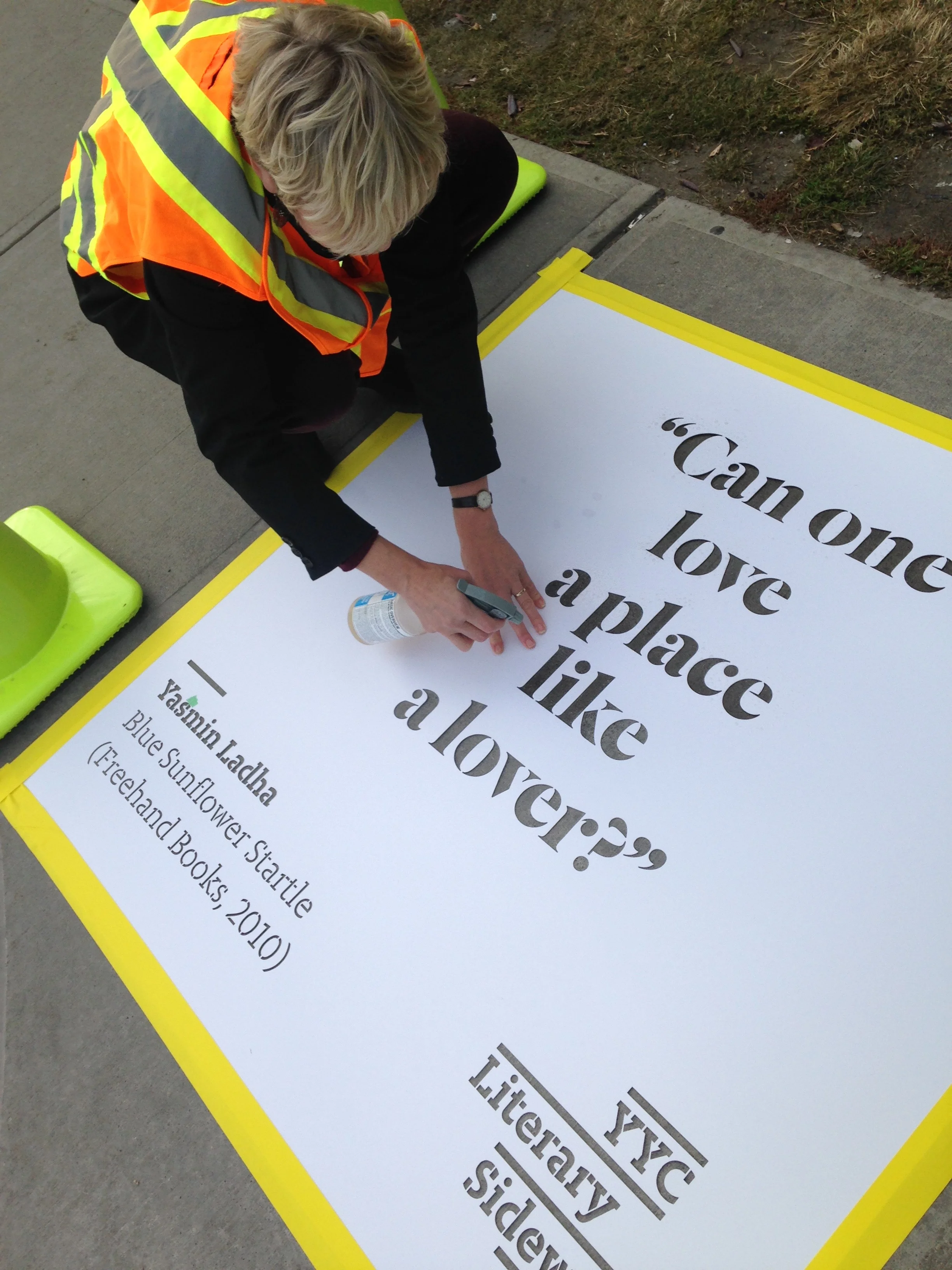 Rosemary Griebel (Calgary Public Library) sprays a quote from Yasmin Ladha's Blue Sunflower in front of the Crowfoot Library. 