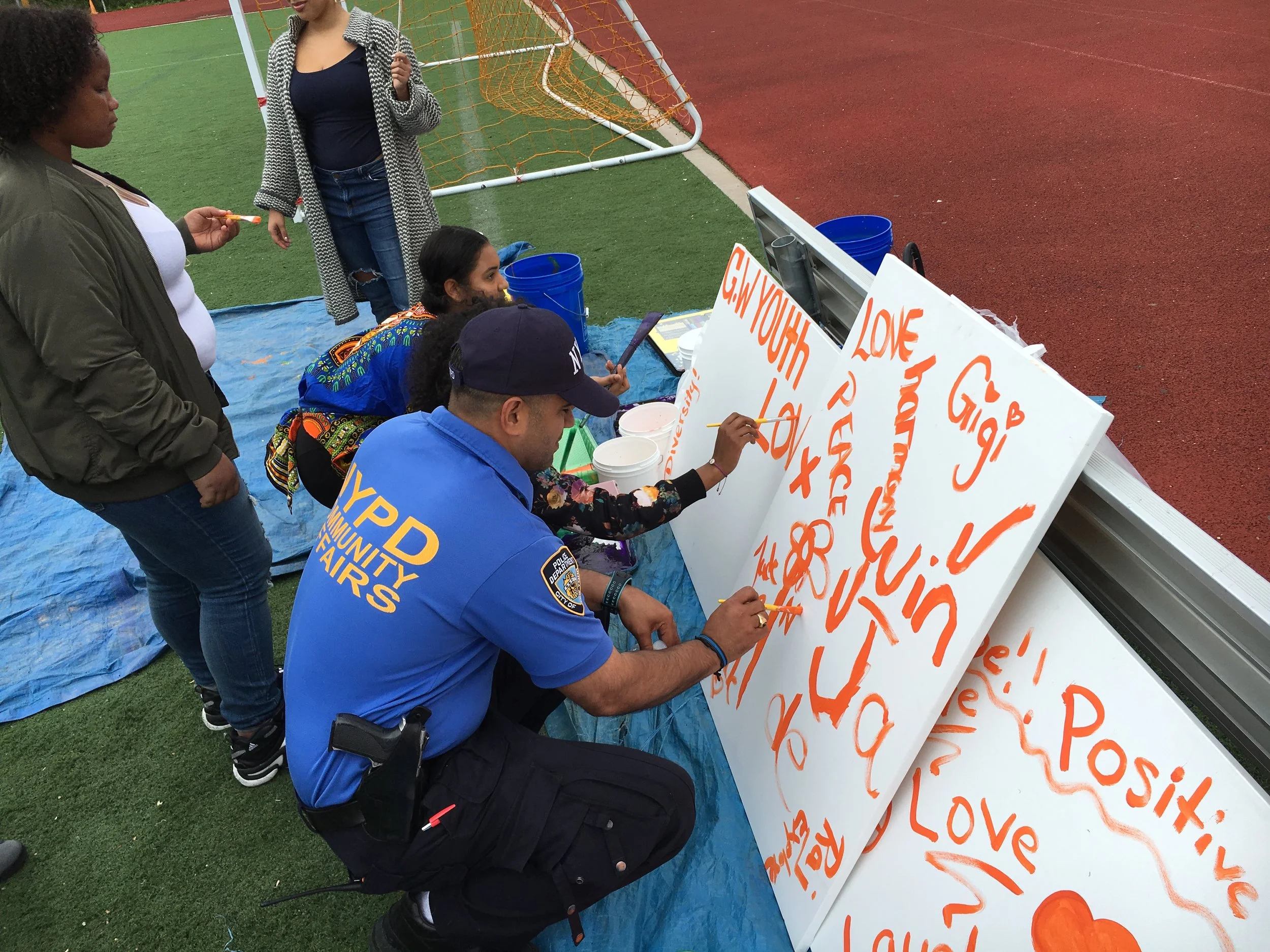 Artist Jamilex Tavares oversees as NYPD, Community members and Youth paint together.