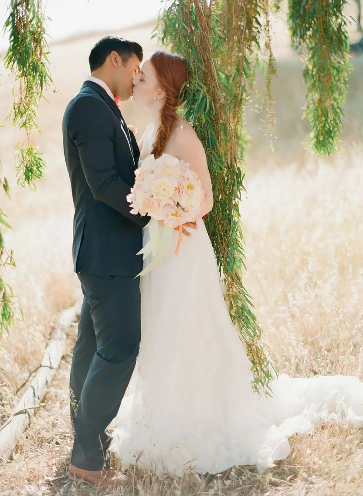 bride and groom standing in a field, bride holding bouquet designed by chandara creative, photo featured on Style Me Pretty