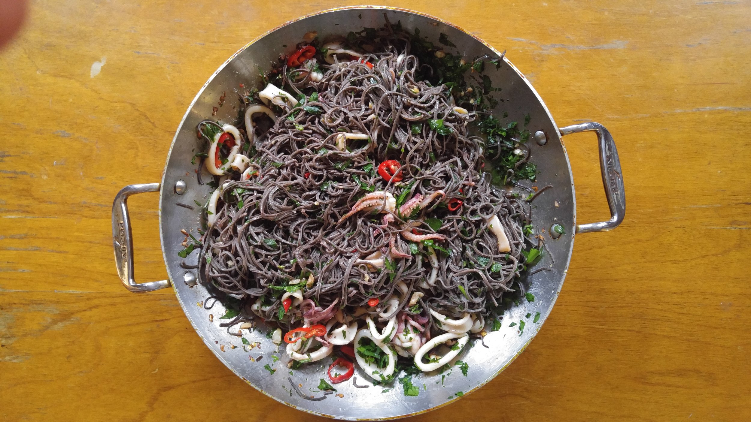 Squid over black bean pasta with jalapenos, parsley and garlic