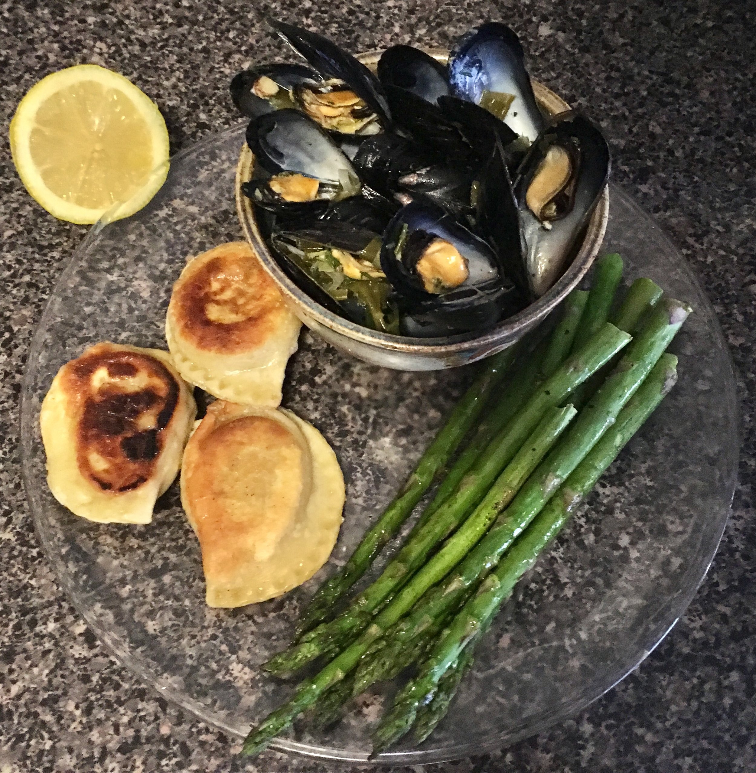 Mussels cooked in a garlic scape and dill white sauce with perogies and asparagus