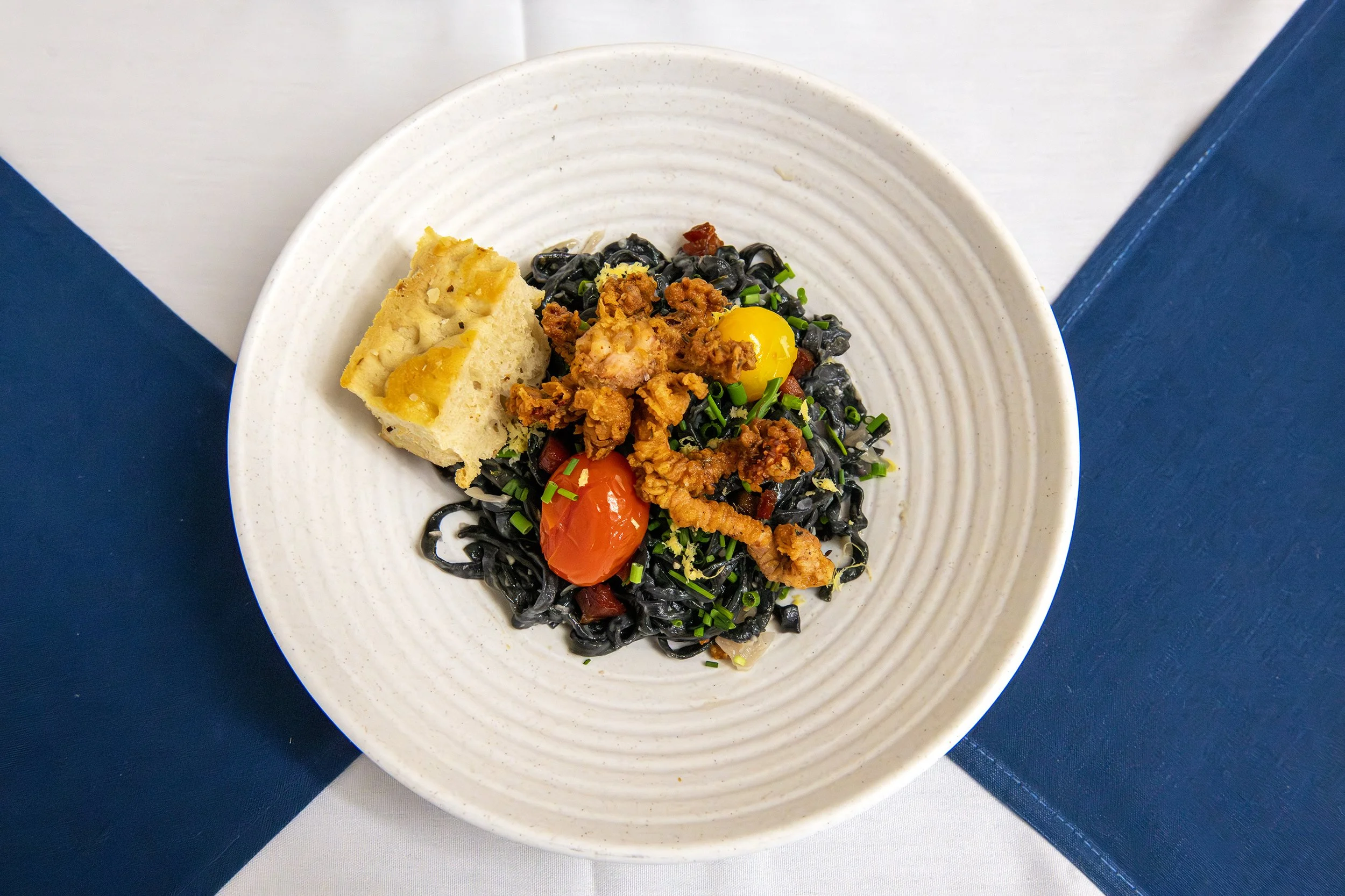 House-made Squid Ink Pasta tossed with Aromatics, Tomatoes and topped with Fried Calamari- East Providence High School Culinary Program