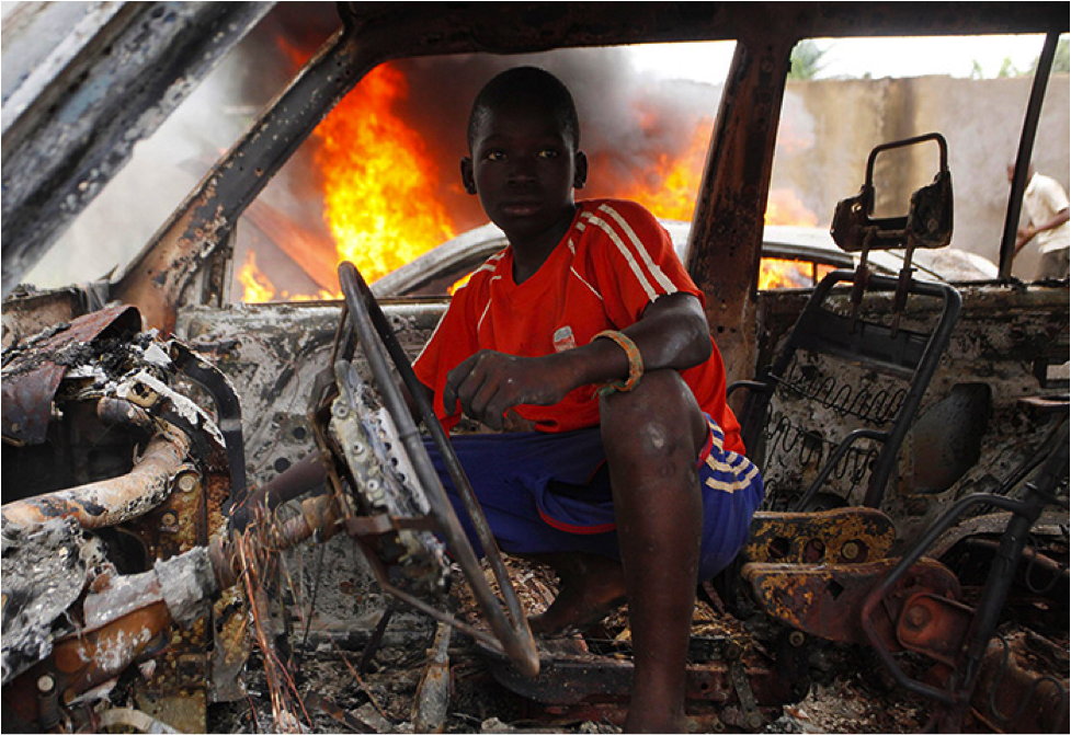 A Christian youth squats inside a burnt-out car in Bangui - Photograph: Emmanuel Braun/Reuters ; Source: The Guardian