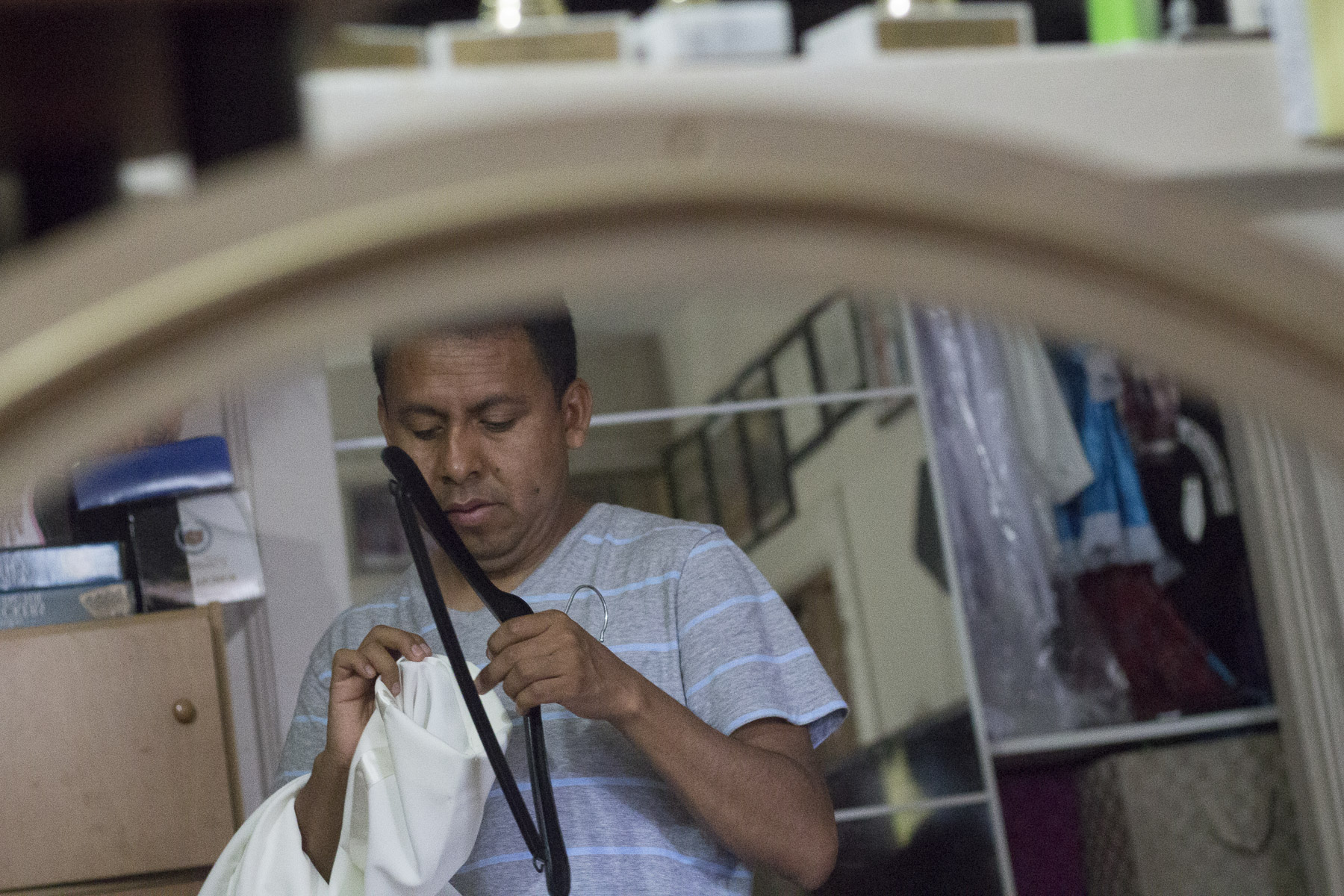 Benito Bravo stands in front of a mirror, putting one of his handmade costumes back on the hanger after making a slight alteration earlier on. Gabrielle Narcisse and Deleelah Saleh for Picture Justice. August 22, 2017.