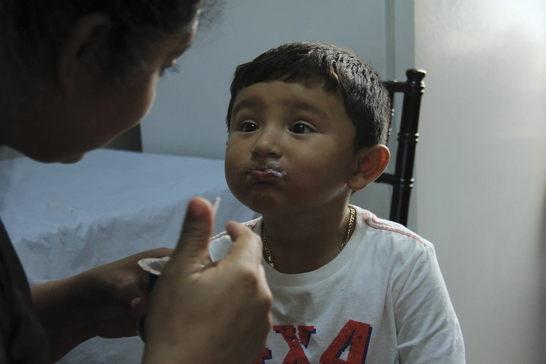 Amanda and her two-year-old son David share a yogurt at lunch time in the church kitchen before he returns to watching his favorite TV show, Dora the Explorer. Holyrood Episcopal Church in Washington Heights, New York – August 17, 2017.