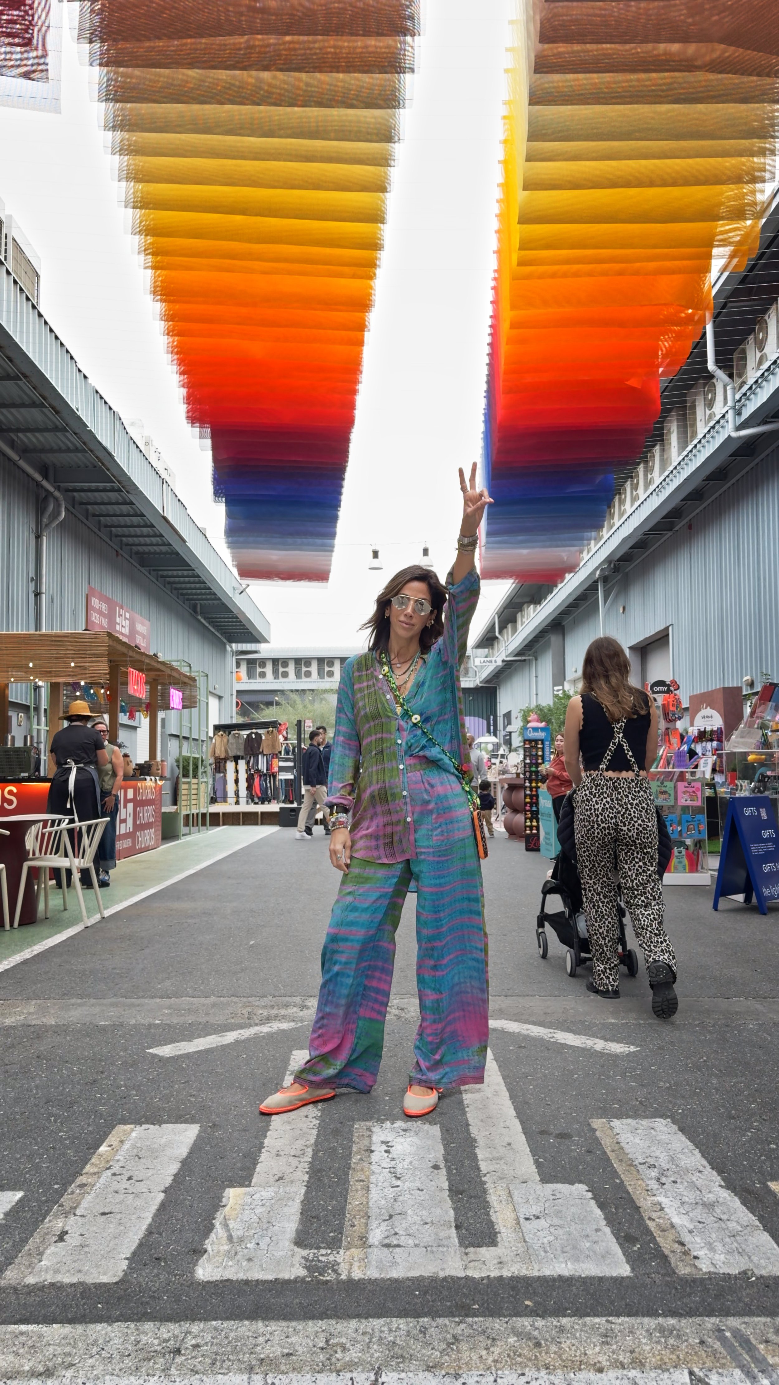 Azizeh designer posing with her hand in a peace sign in a Dubai art market