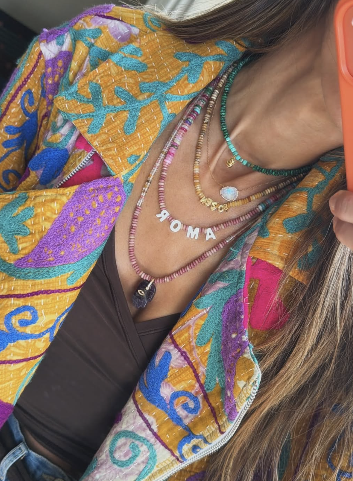Close up of a womans chest showing handmade jewelry and a kantha fabric jacket collar