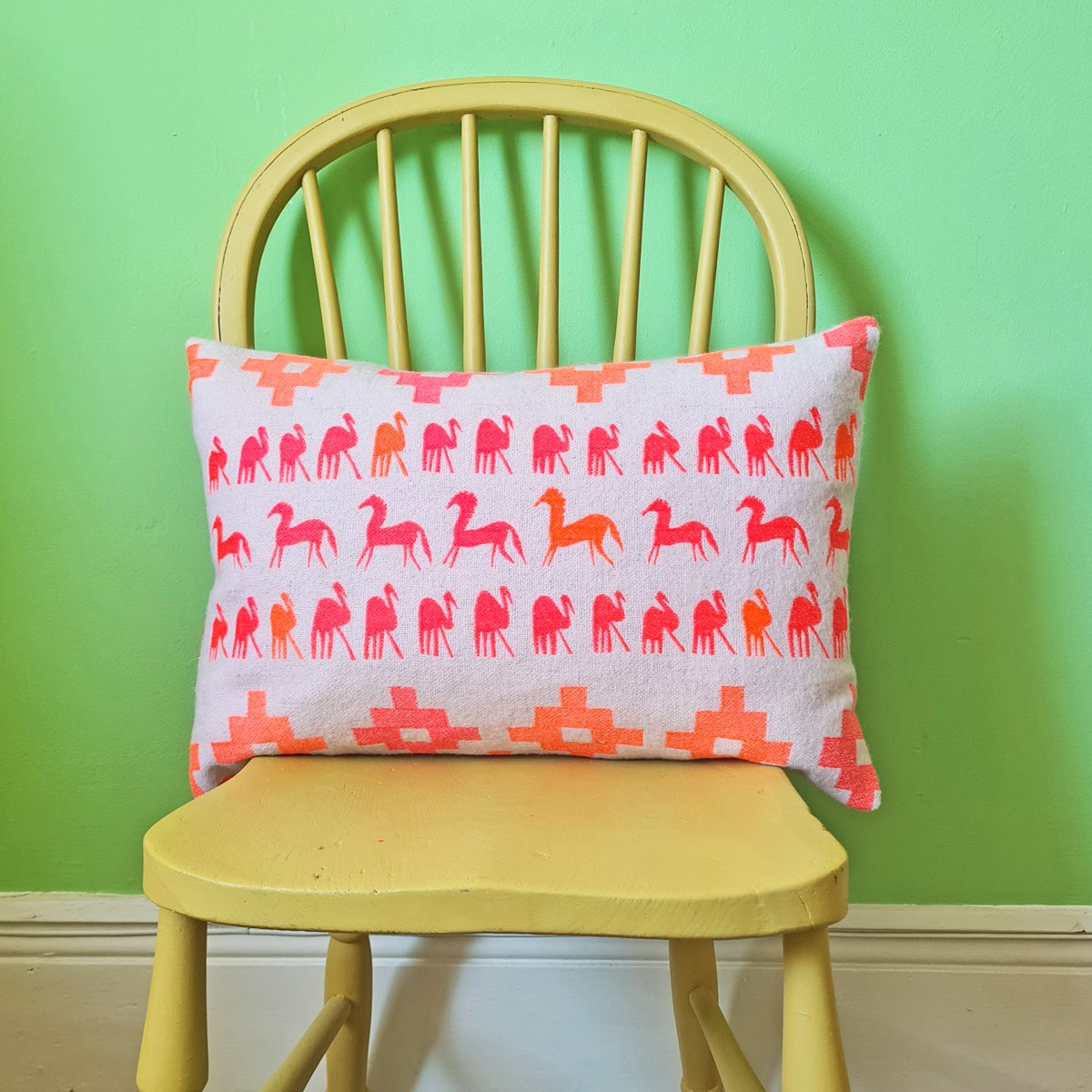 pink and orange embroidered cushion with horses and birds
